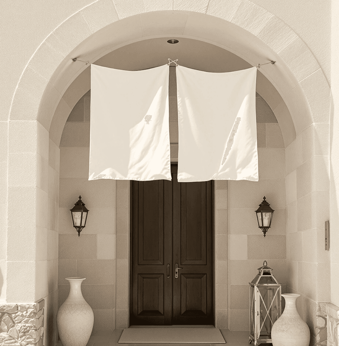 Elegant arched entryway with dark wooden doors, white drapes, and decorative lanterns