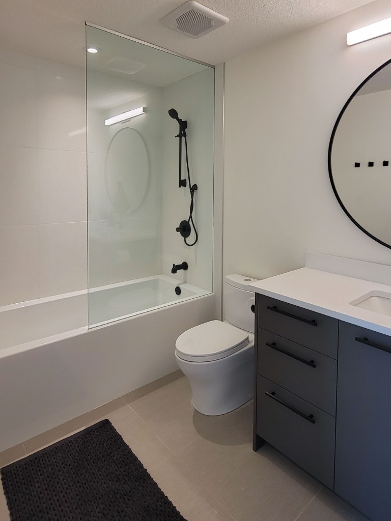 Image of Modern primary ensuite bathroom with gray cabinets, white countertop, and spa-like shower by KHD Homes.