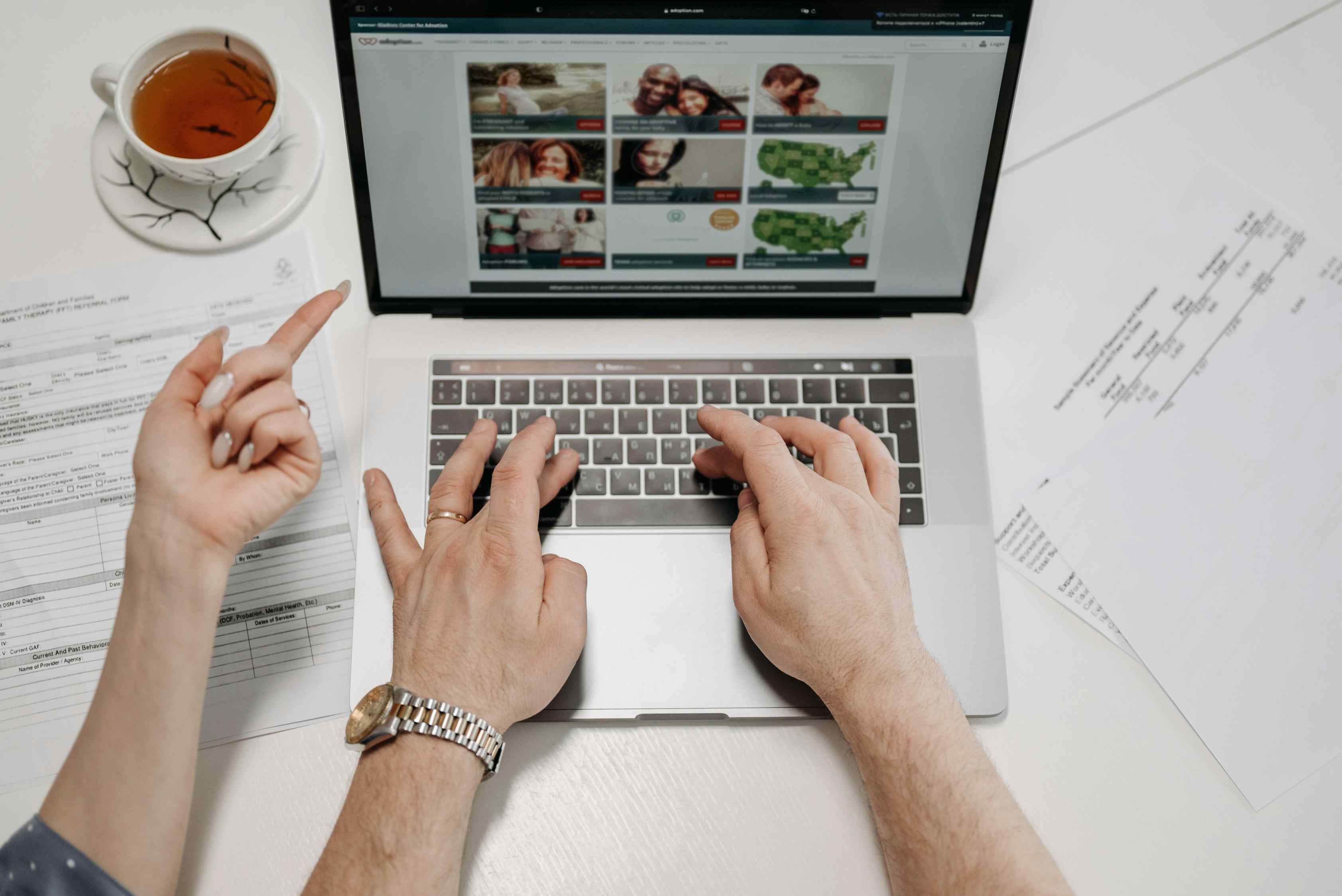 Hands typing on a laptop while browsing a web portal interface