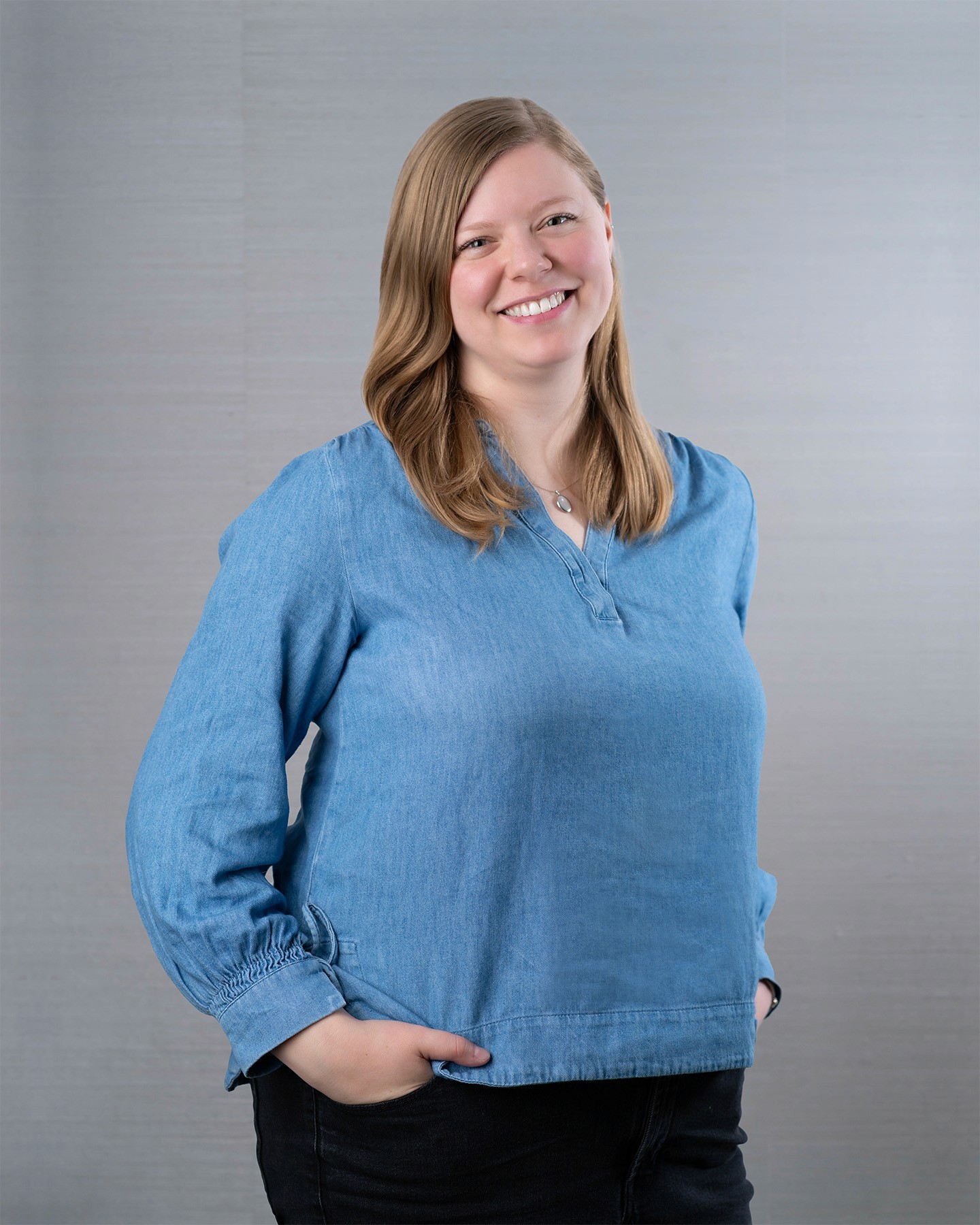 Friendly blond woman wearing long sleeve blue shirt.