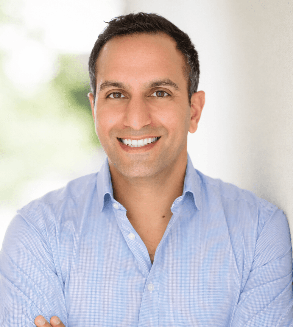 A woman with long dark hair wearing a black hijab, looking calmly at the camera against a muted background.