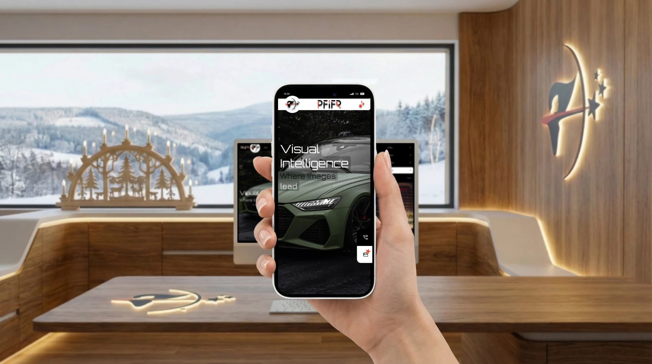 Hand hält ein iPhone mit der mobilen Ansicht der Website PFiFR® Visual Intelligence, dargestellt vor einem modernen Office-Interior mit Holztisch, iMac-Arbeitsplatz, großer Fensterfront und winterlicher Landschaft im Hintergrund.