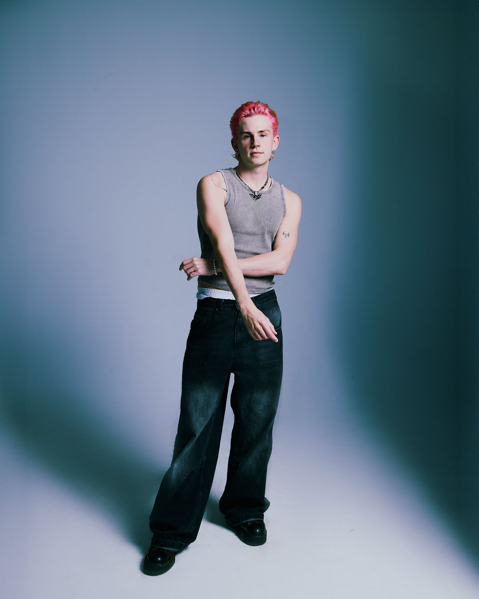 Woman posing by a gas station sign at night