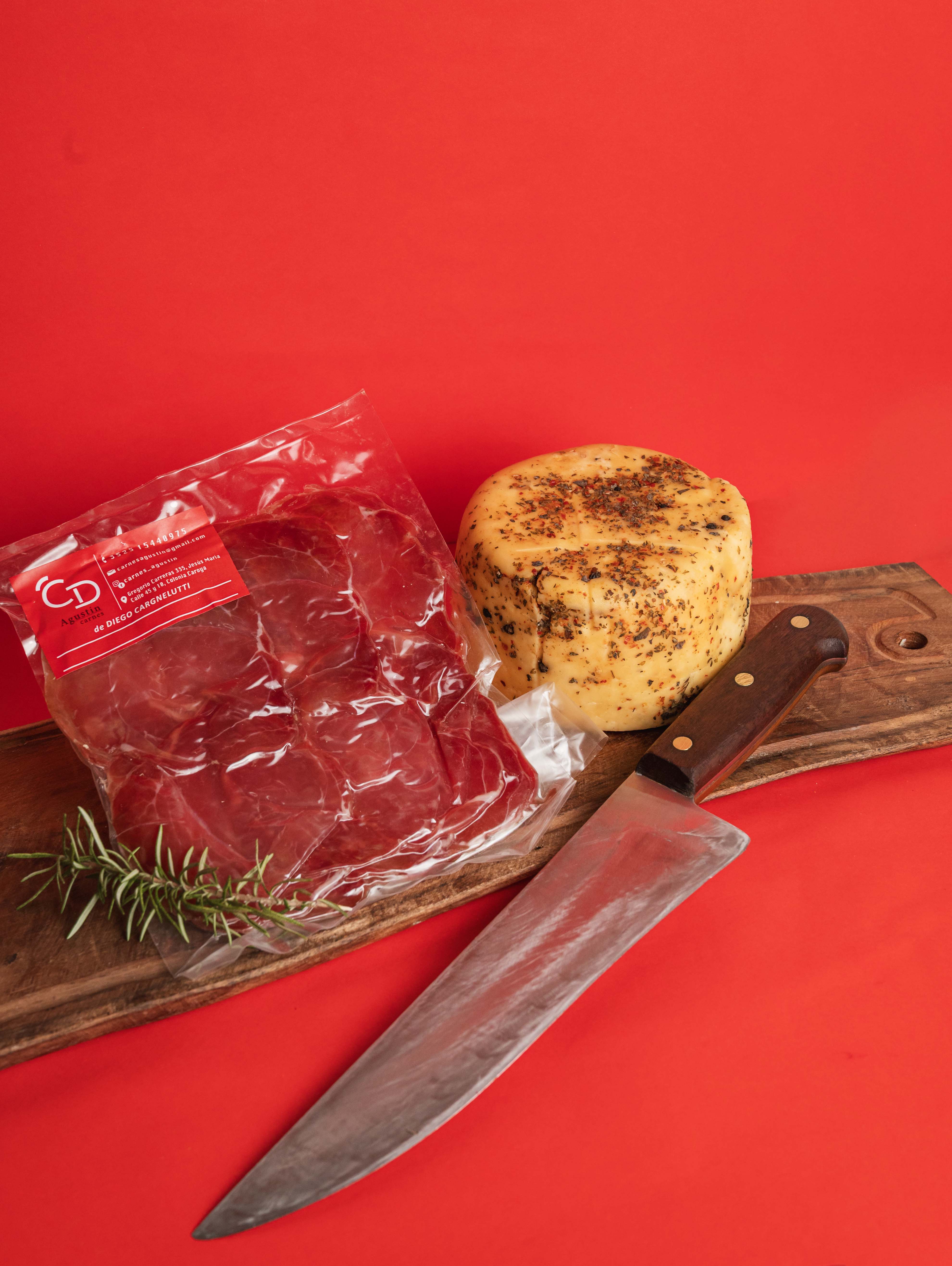 person in red and white long sleeve shirt slicing meat