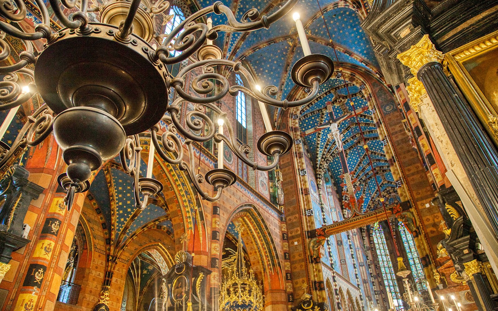 Krakow church interior with ornate chandelier and colorful vaulted ceiling.