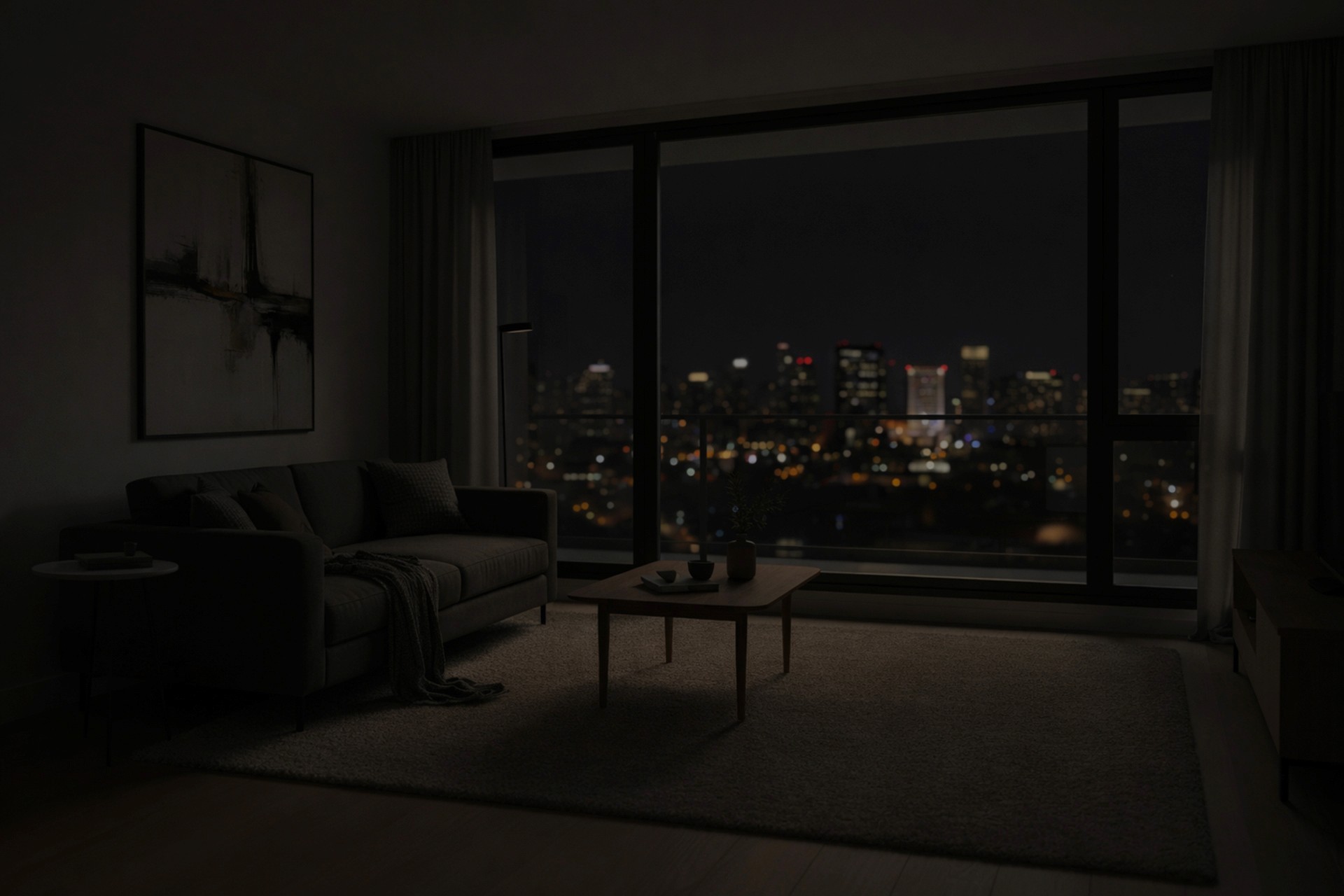 A dim, modern living room at night featuring a grey sofa and wooden coffee table, with a glowing city skyline visible through a large window.