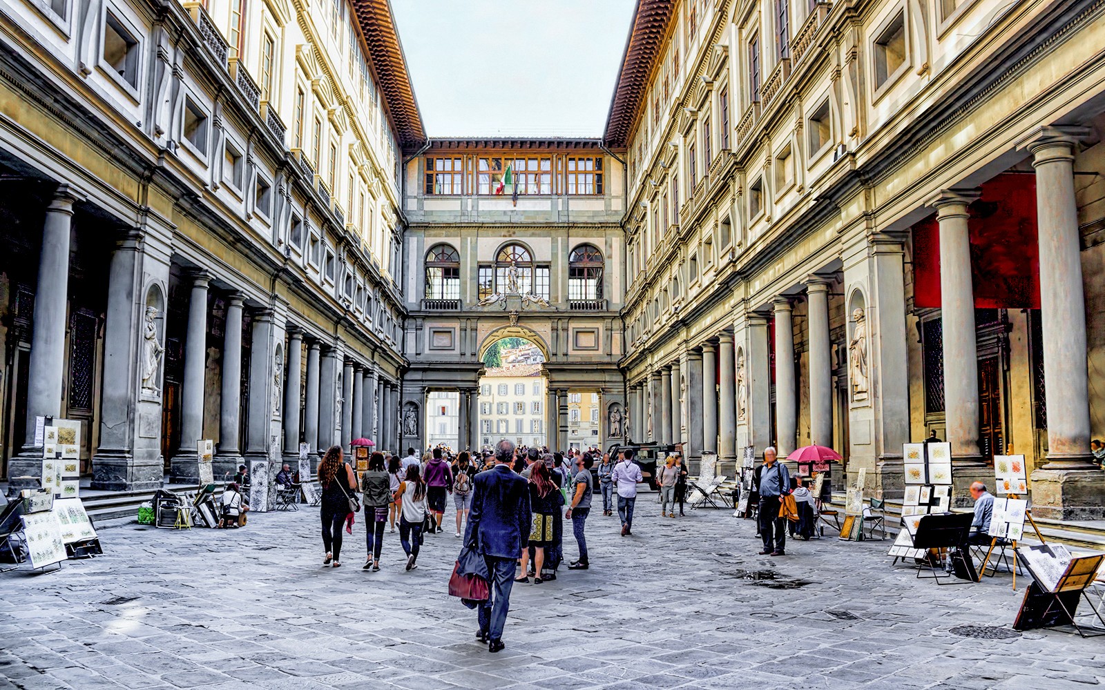 People walking through the arcade of the Uffizi Gallery in Florence, Italy.