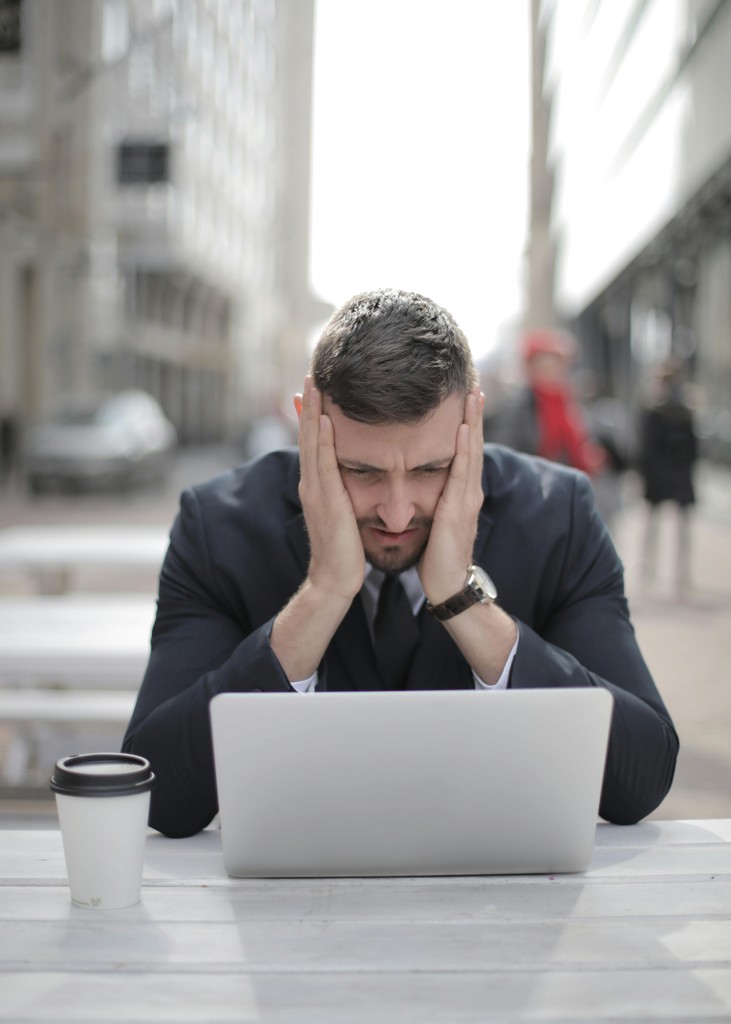 A stressed newcomer woman in a Canadian apartment looking overwhelmed while viewing her take-home pay or high rent costs on a laptop, representing the financial reality of living on a $100,000 salary in Toronto or Vancouver.