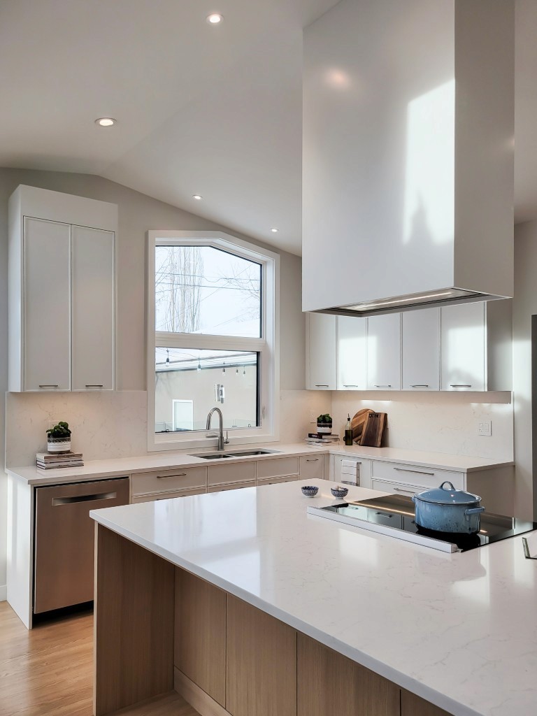 Image of Modern kitchen interior with white cabinets, marble countertops, and induction cooktop by KHD Homes.
