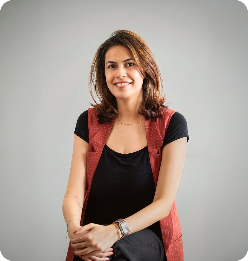 woman in blue denim jacket and white skirt standing beside brown wooden table