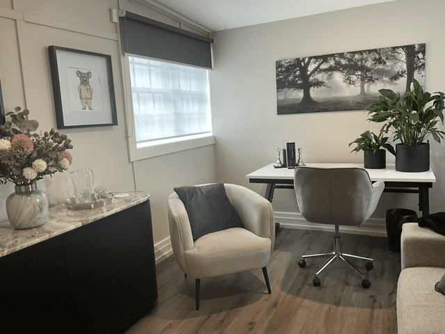 A vacant room with wooden flooring, a sloped ceiling, and a window letting in natural light.