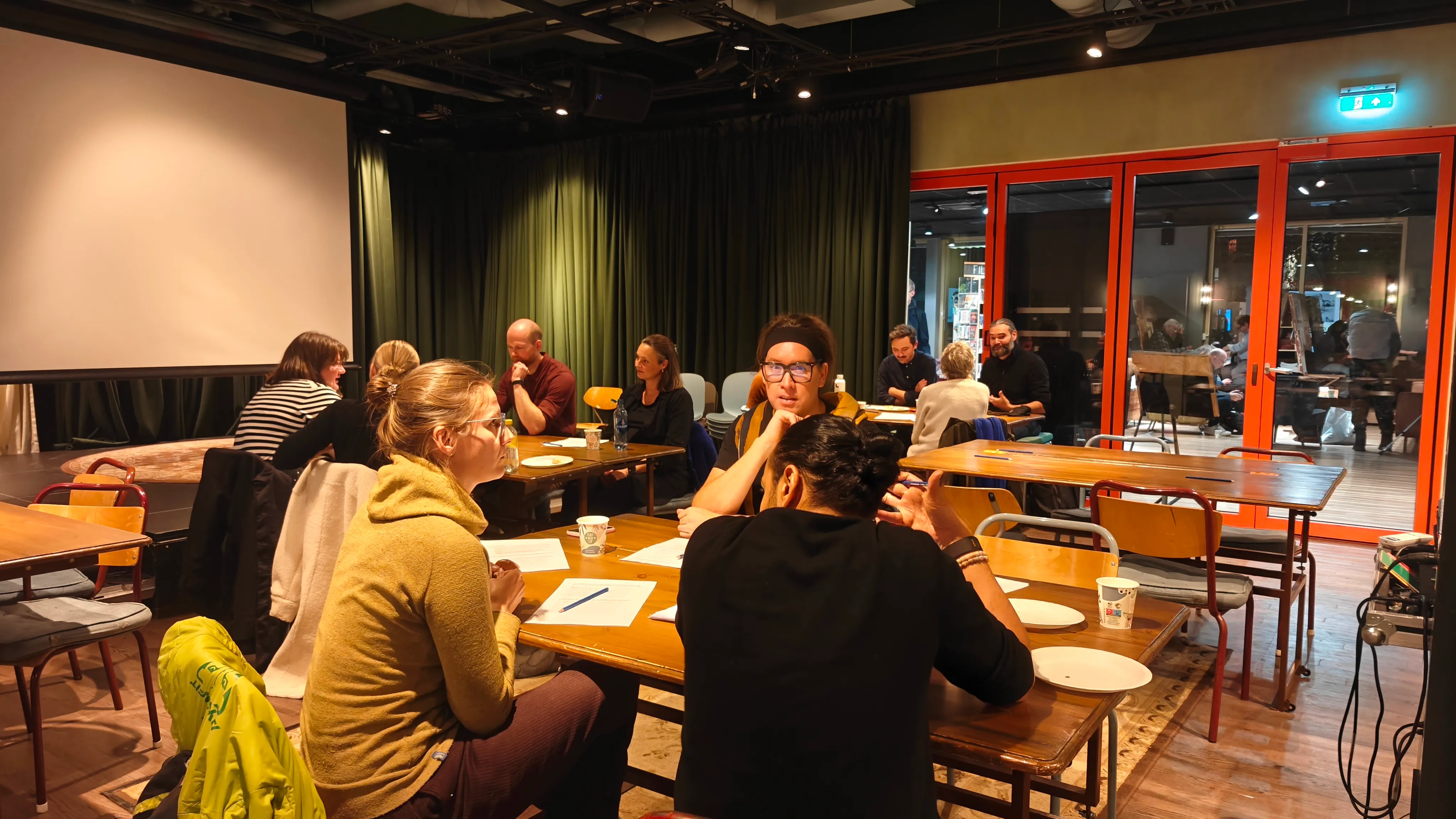 Several groups of people sitting down and talking around tables in a room