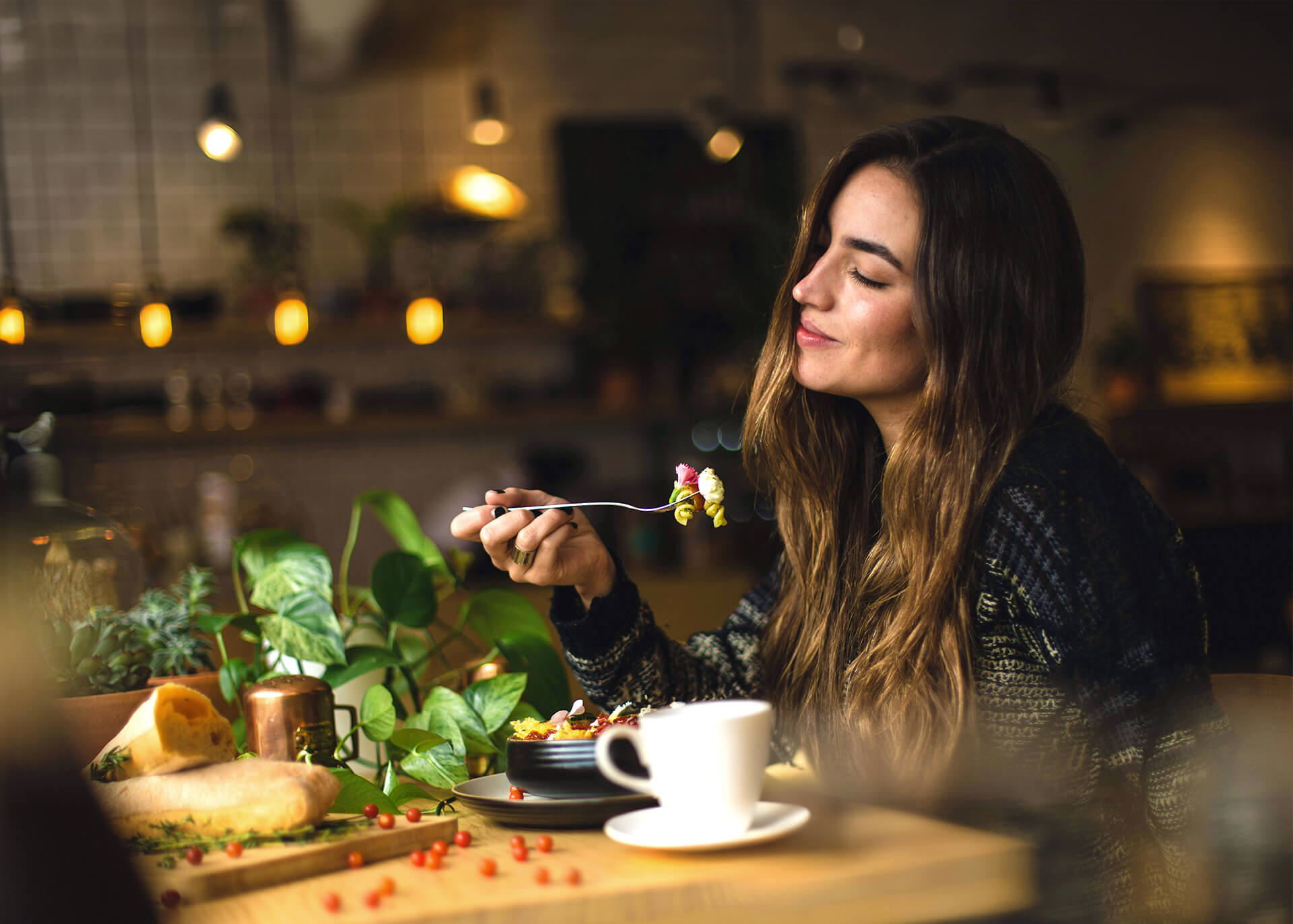 Frau genießt entspannt ihr Essen in einem gemütlichen Restaurantambiente