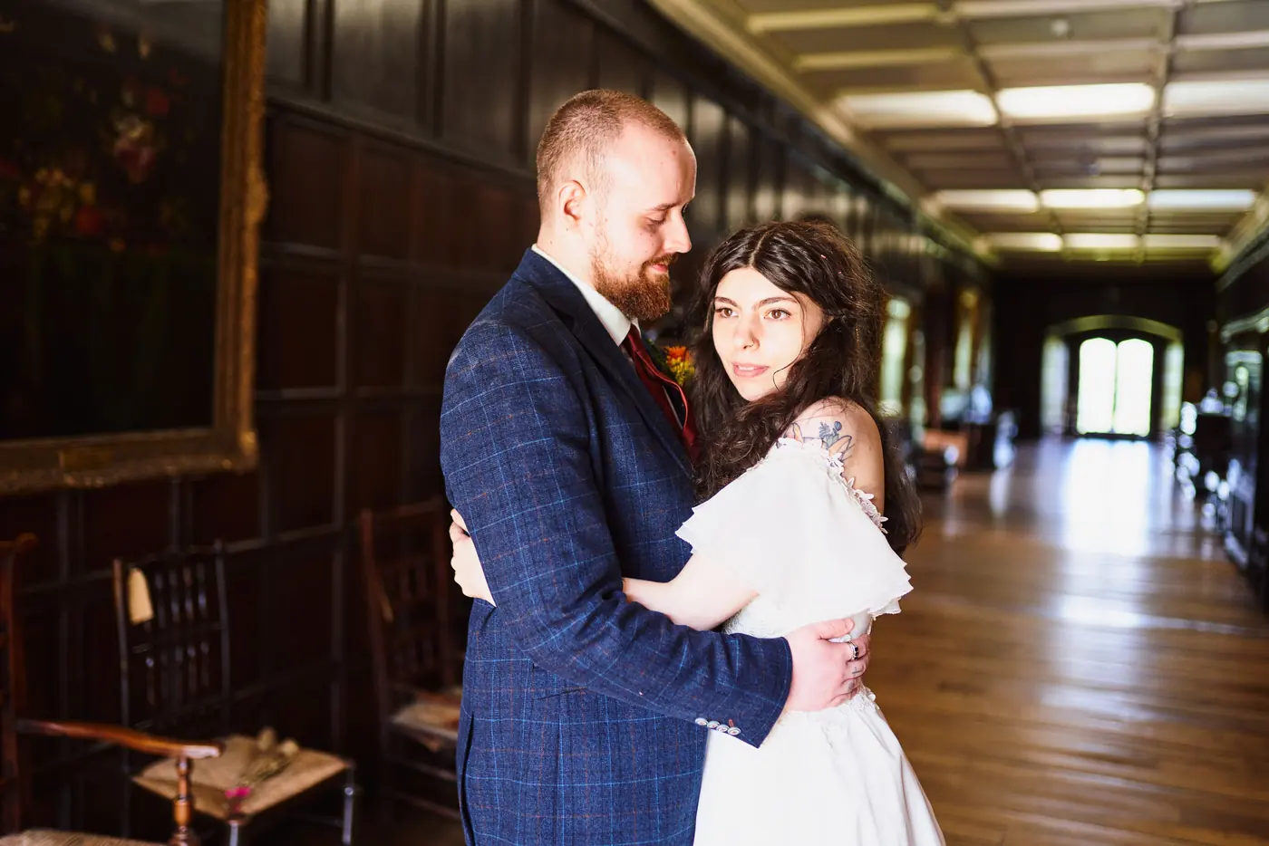 Bride and groom hugging in a wood-panelled gallery at Towneley Hall
