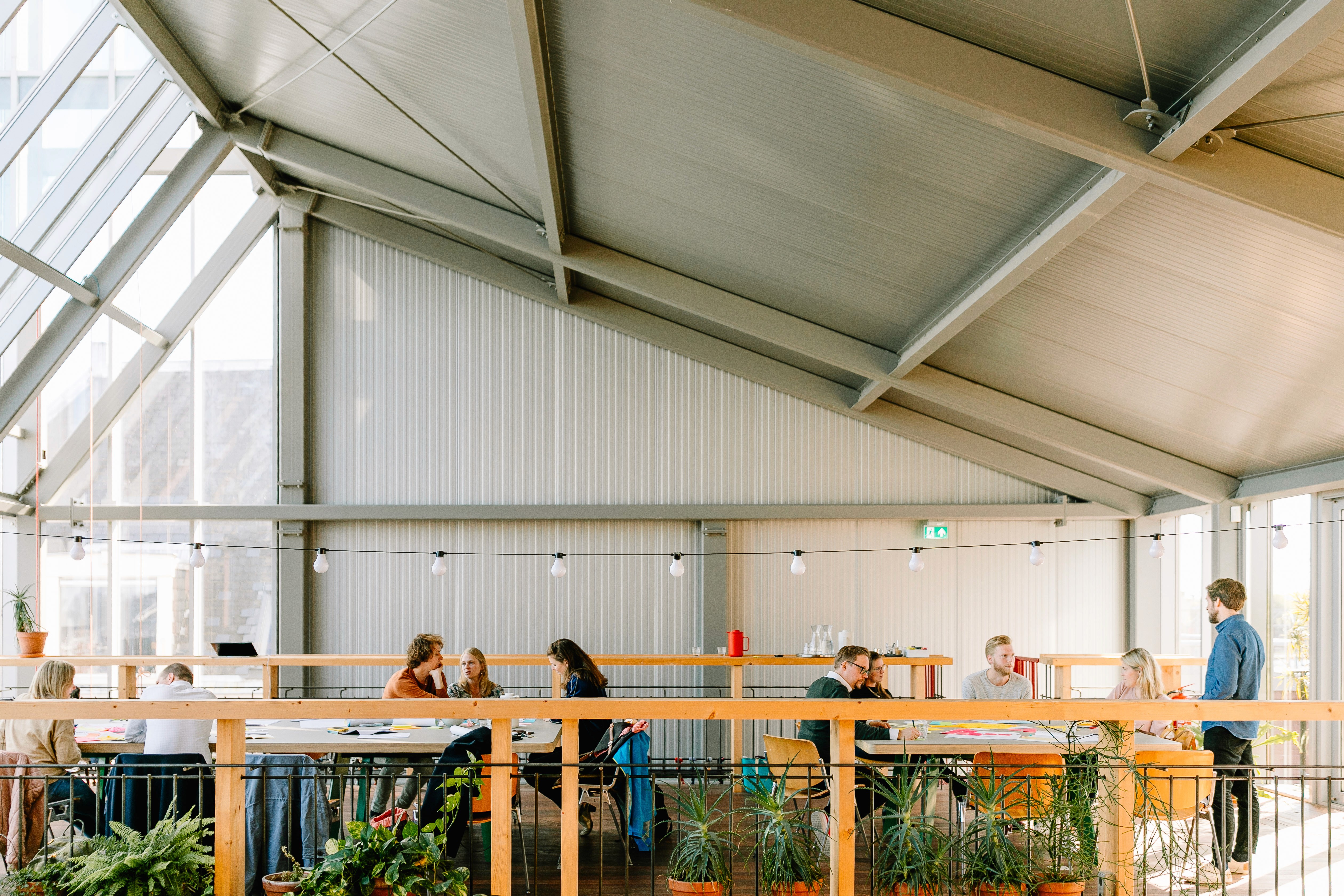 Black and white image of people working at a table with laptops, showing hands gesturing during discussion of digital content displayed on screens, with fabrica® logo in the corner.