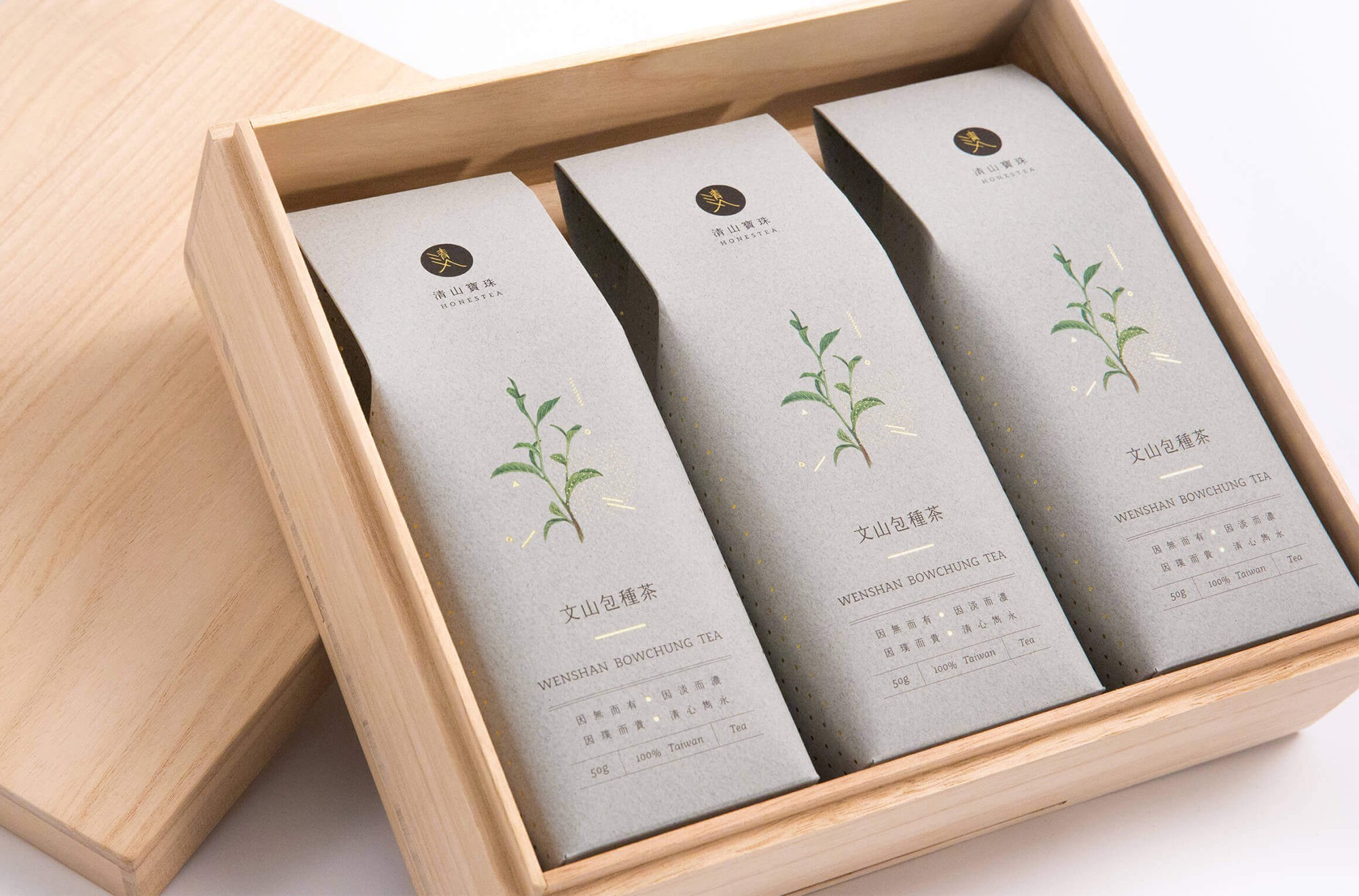 這張圖像展示了清山寶珠茶葉禮盒包裝設計。木盒裡裝著三條長型小包裝，每個包裝上都有黑色圓形色塊和燙金識別，以及手繪茶葉的水彩插畫。