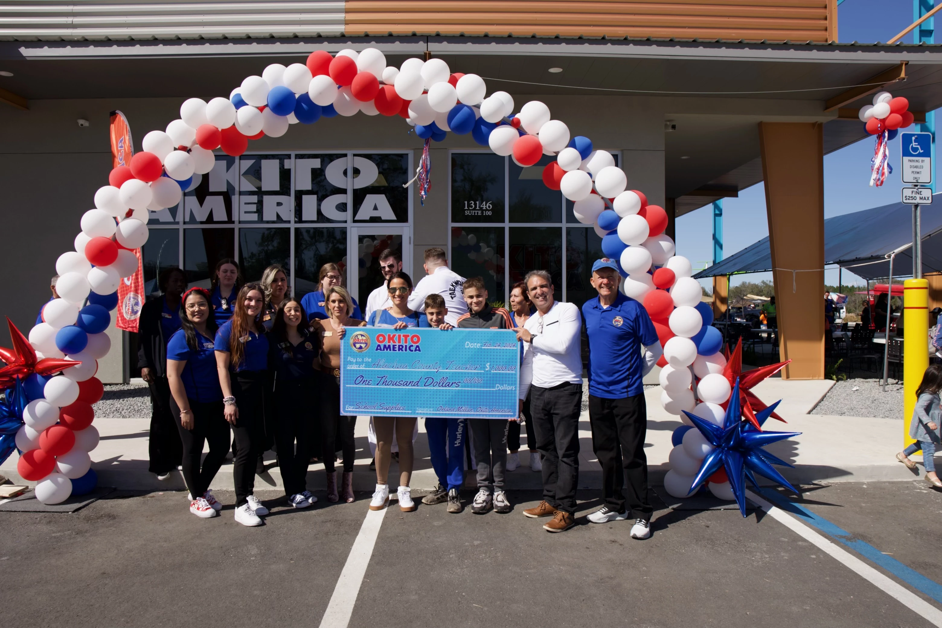 Team members holding a donation cheque in front of Okito Alachua location