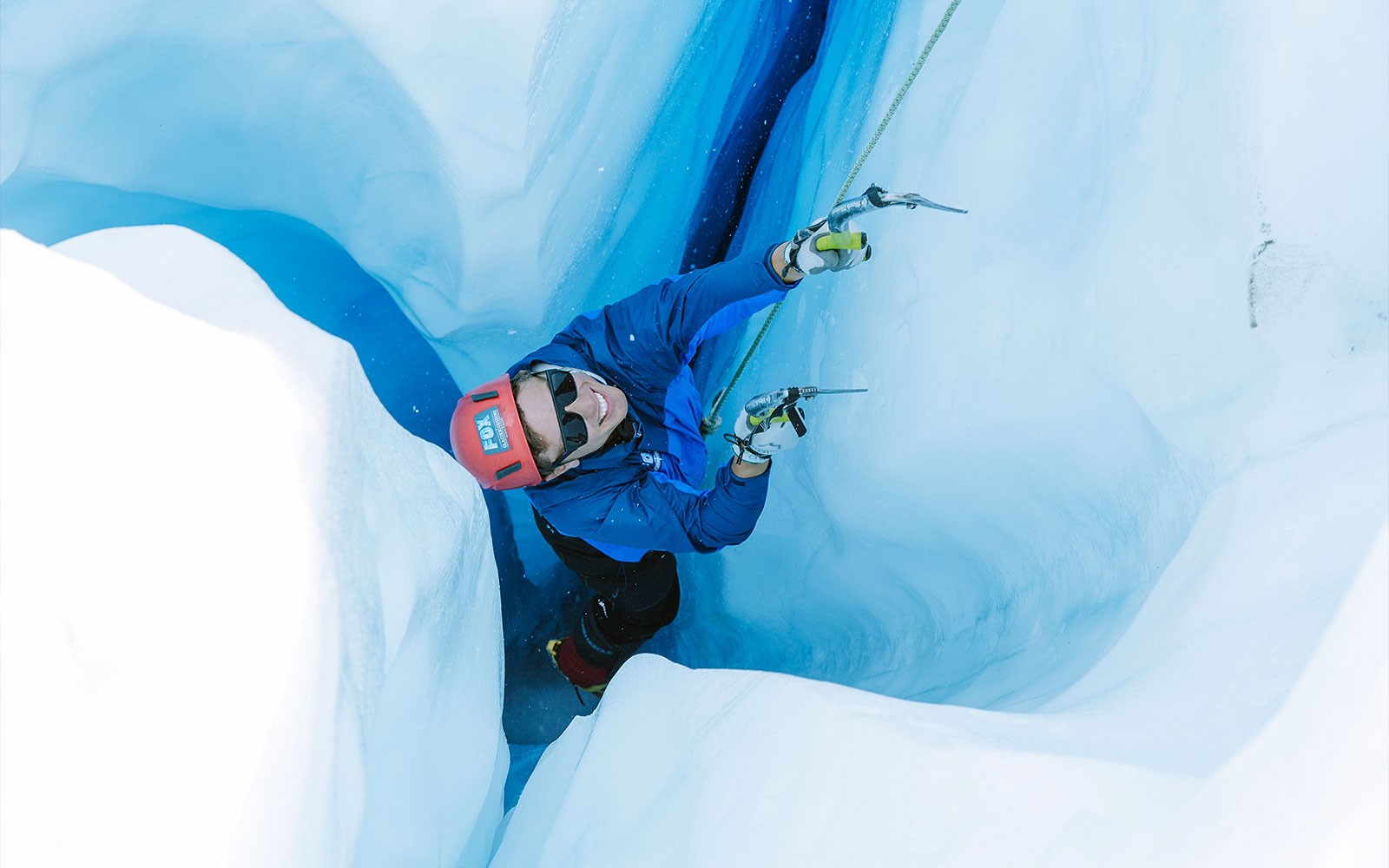 Escalador ascendiendo una grieta helada durante la caminata en helicóptero por el glaciar Fox en Nueva Zelanda.