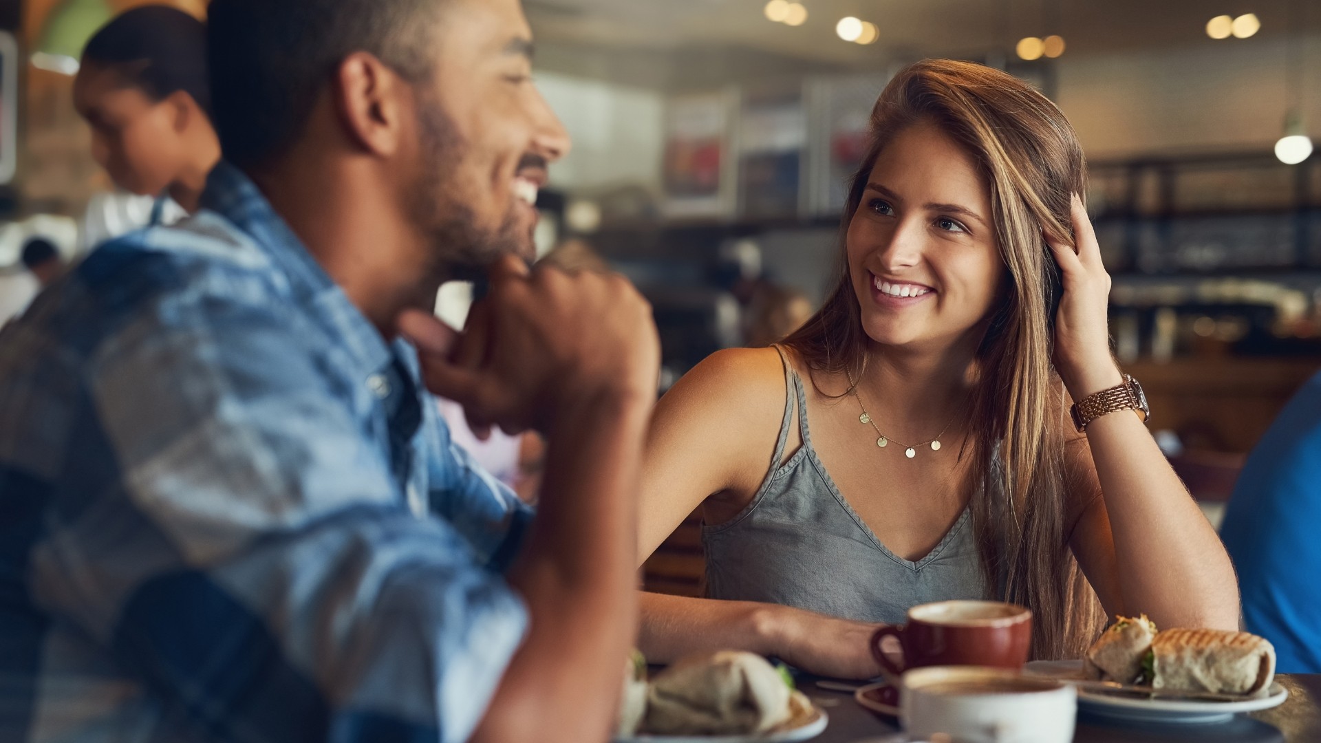 ein mann und eine frau sitzen in einem caffee und trinken und essen gemeinsam, beide sind glücklich