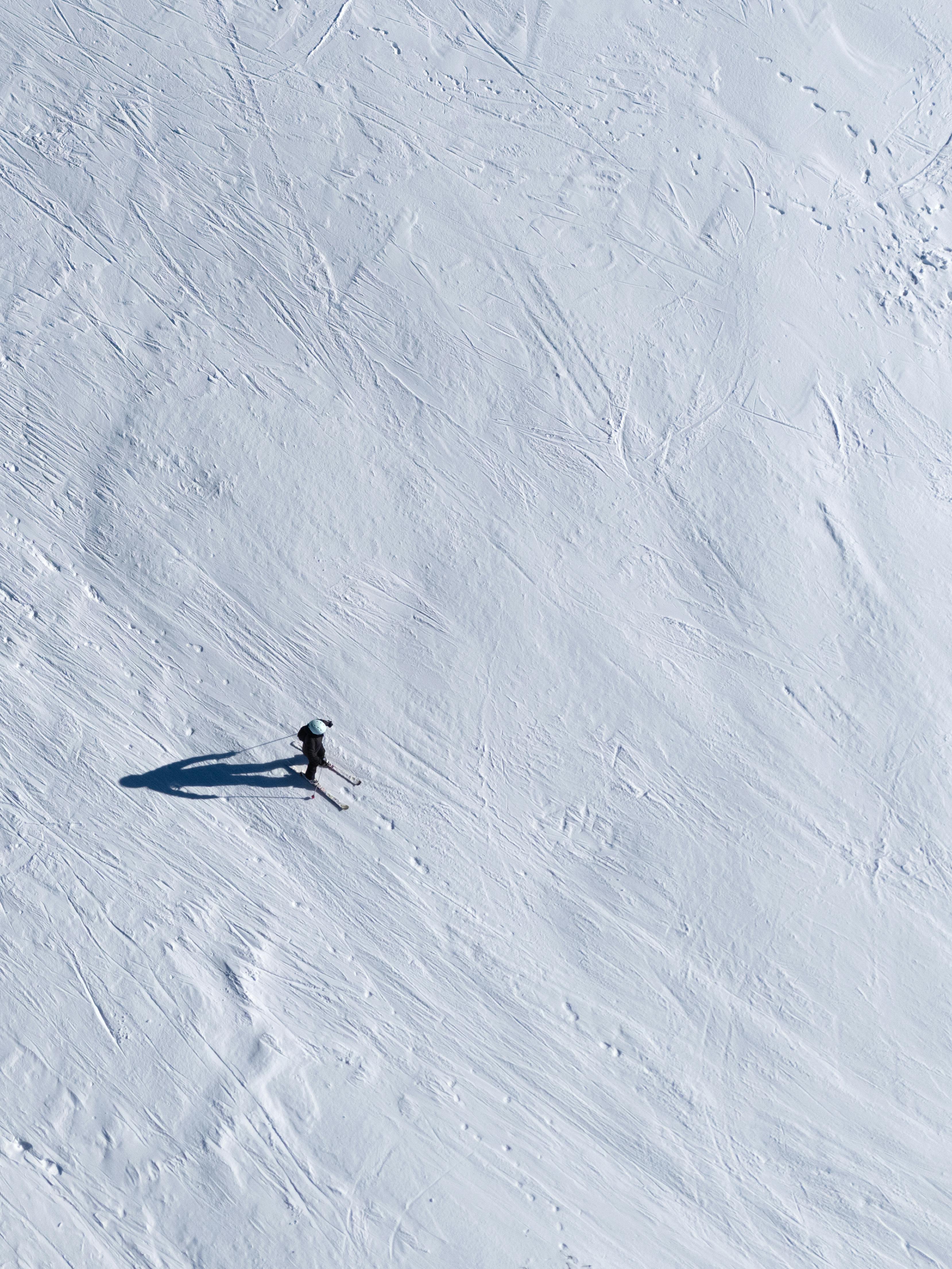 Single person casting long shadow on snowy surface
