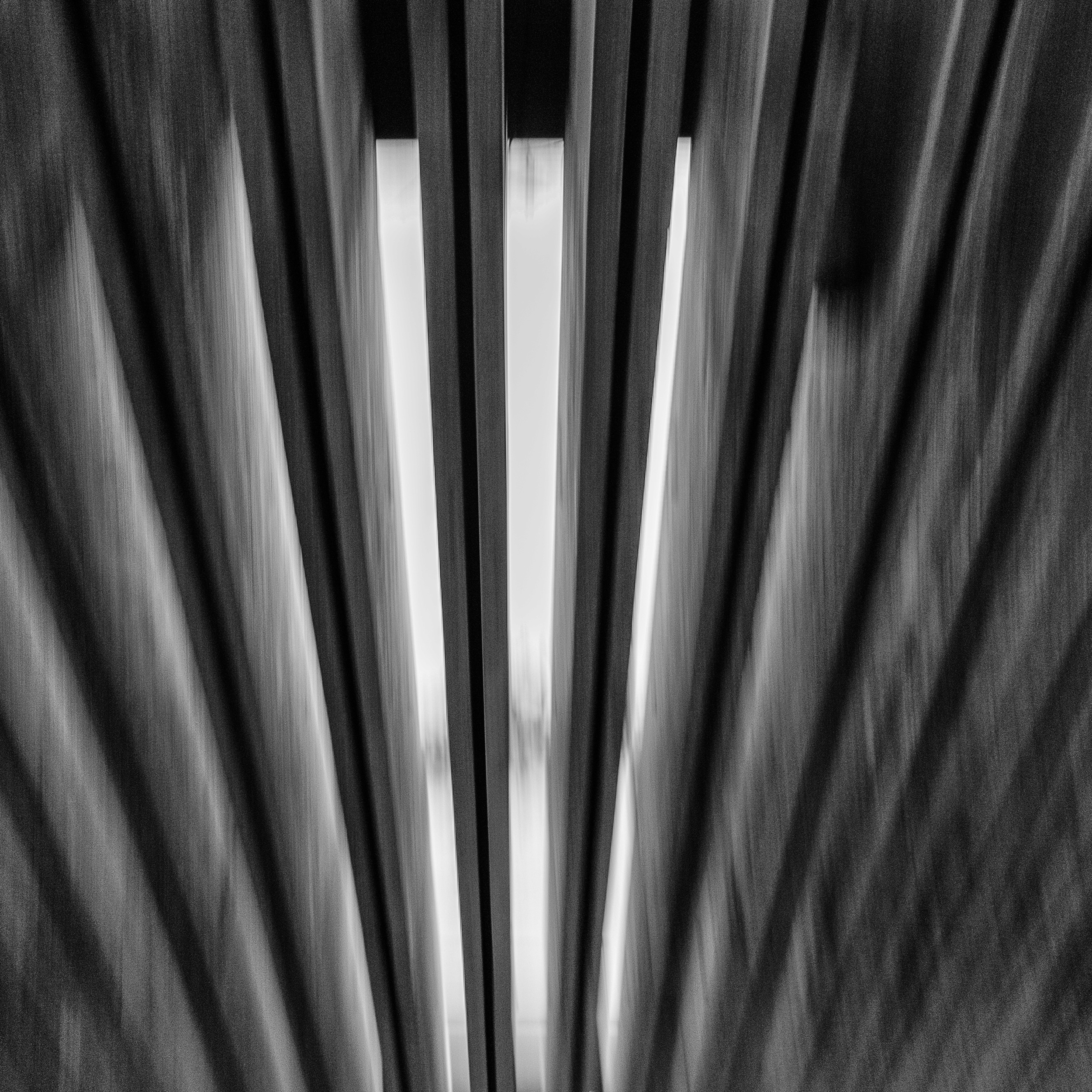 Black and white abstract photo of the wooden canopy roof at Museo Anahuacalli, shot from below with dramatic light and motion blur between the beams.