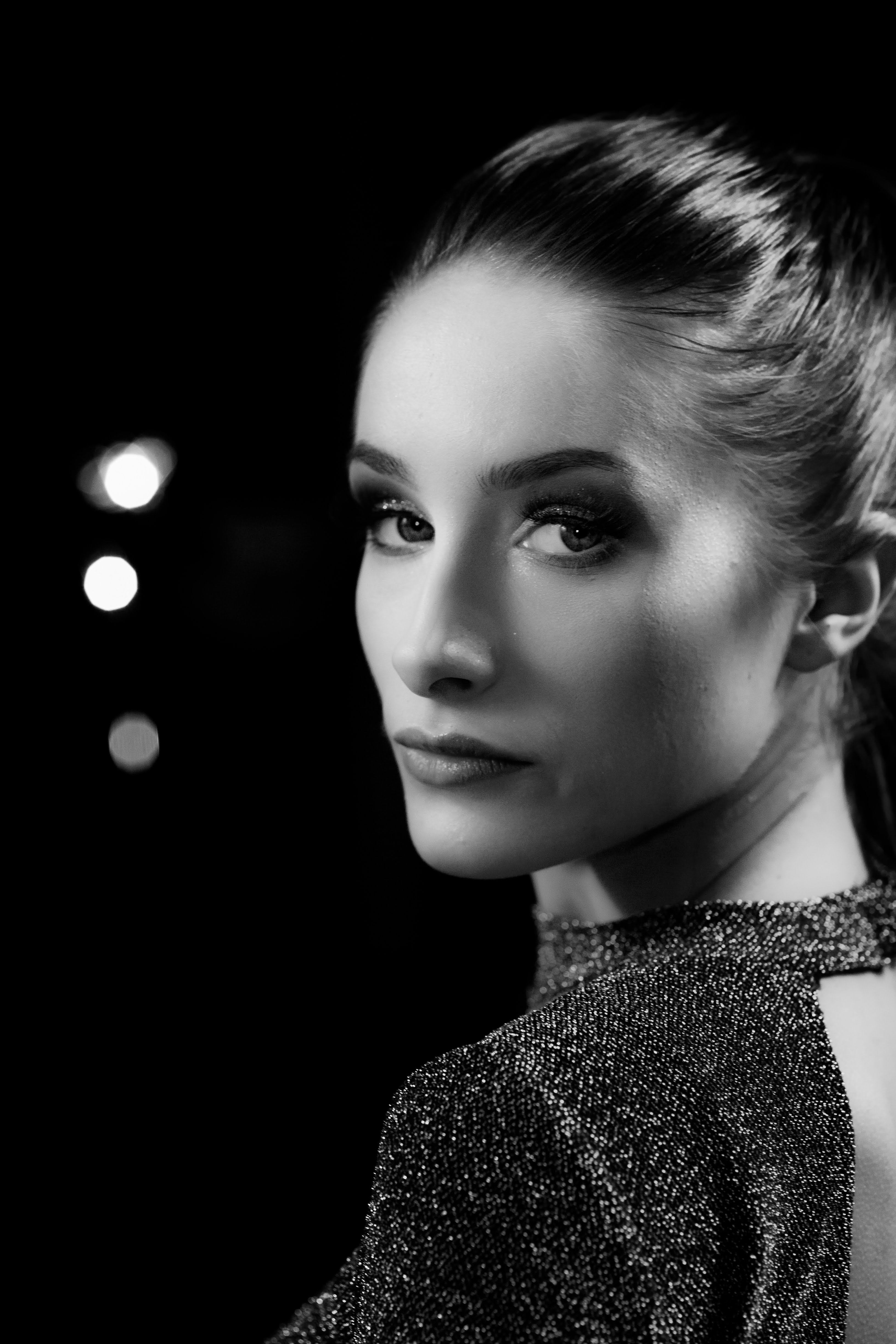 Green car under neon lights in a rainy city street
