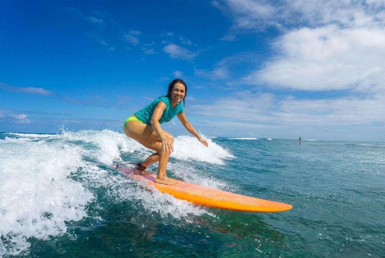 A young woman surfing the waves in tropical Fiji