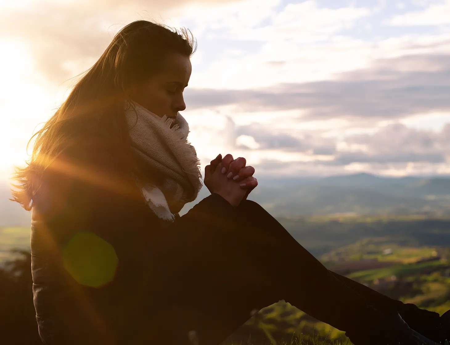 Bilde av kvinne som ber ute i naturen.