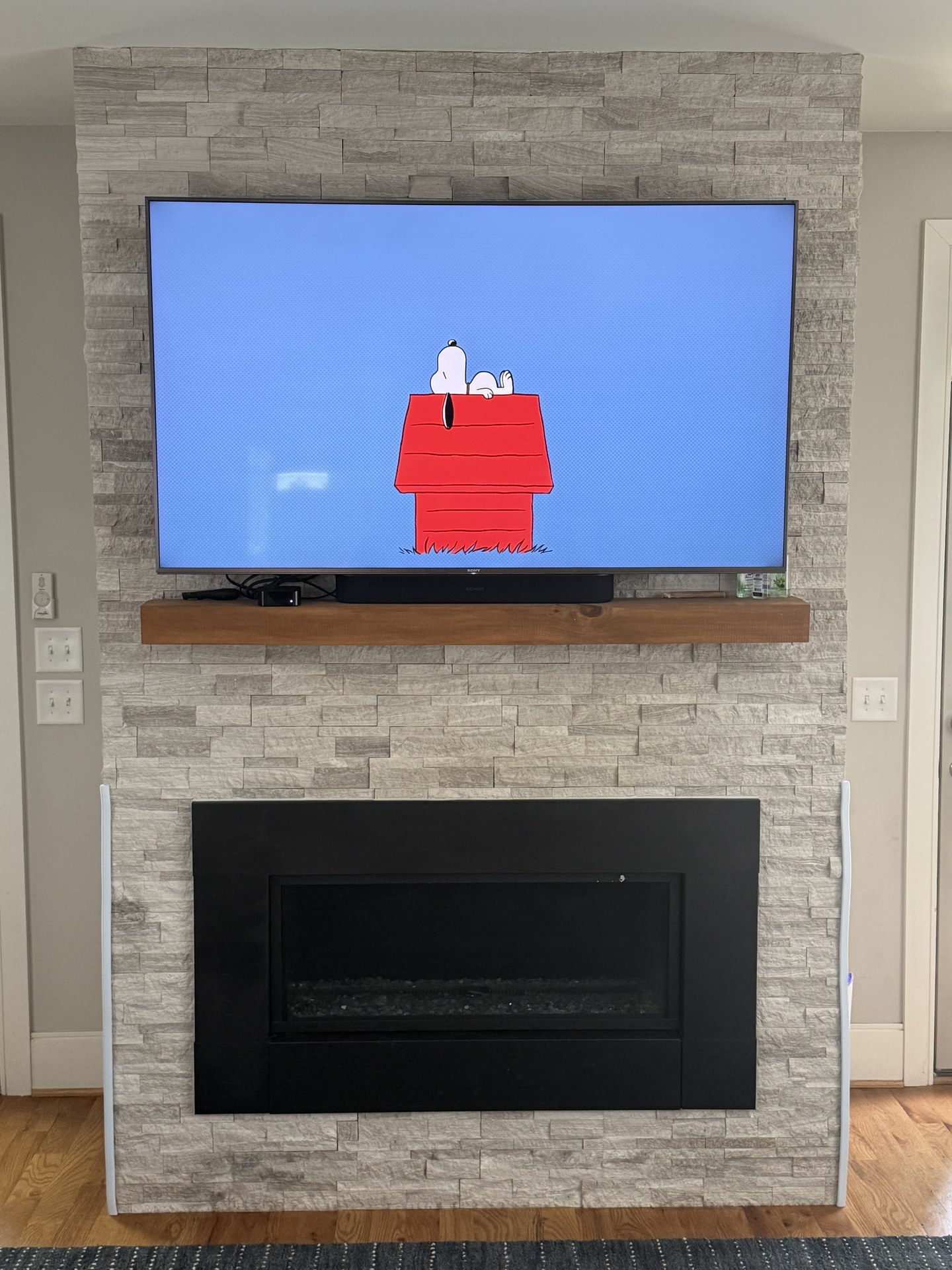 Television centered above a mantel on a textured accent wall.