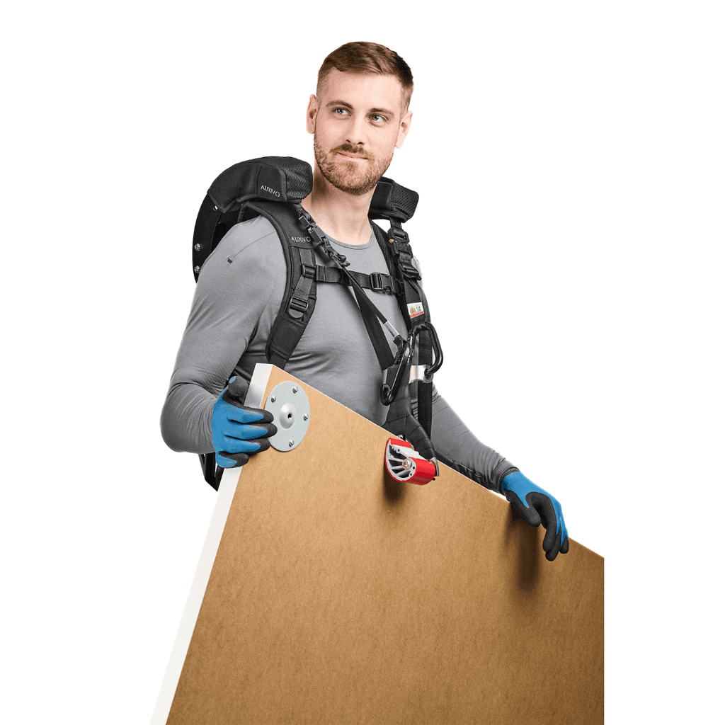 Man equipped with a CarrySuit exoskeleton carrying a wooden panel, designed to reduce back pain and improve efficiency in physical work and handling.