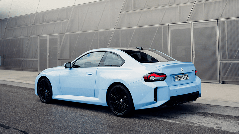 Blue BMW M2 parked in front of a grey wall