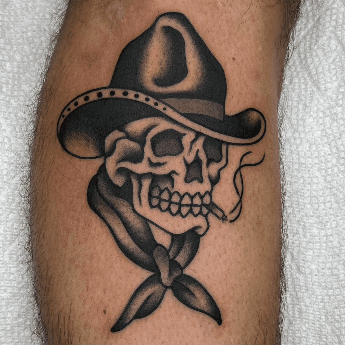 black and gray tattoo of a cowboy skull