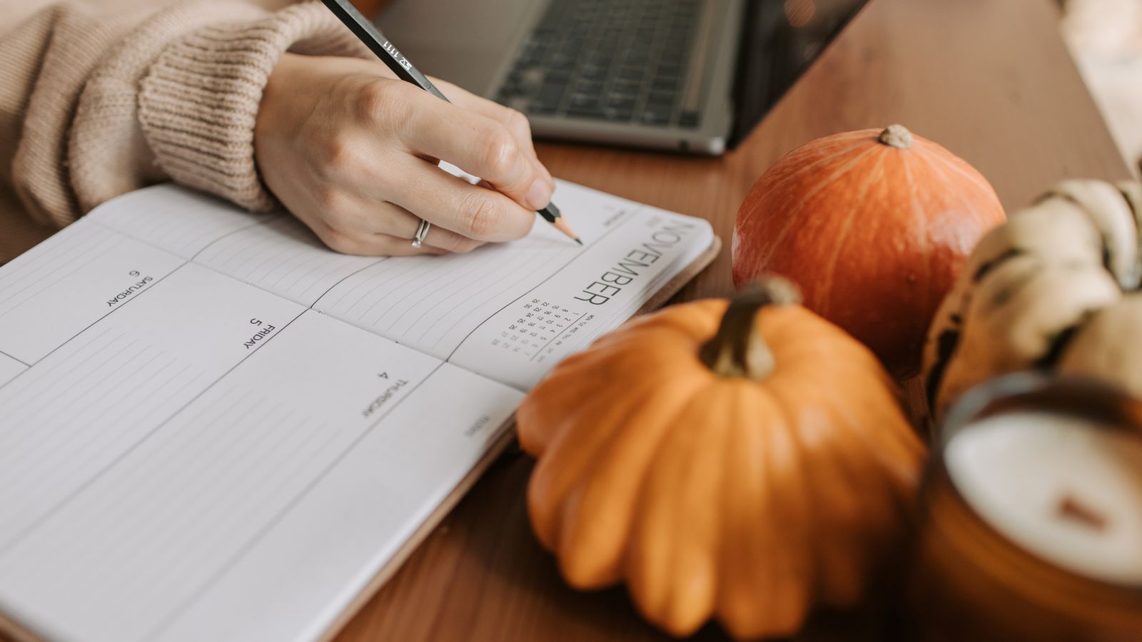 A cozy workspace with a planner, pumpkins, and a laptop, capturing the essence of autumn planning.