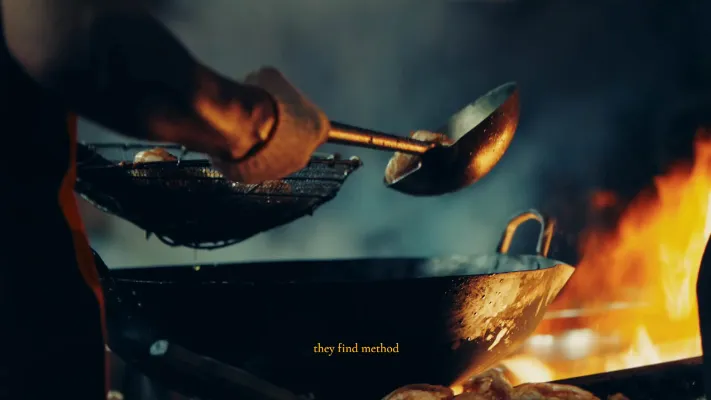 A man cooking with a pan on flames