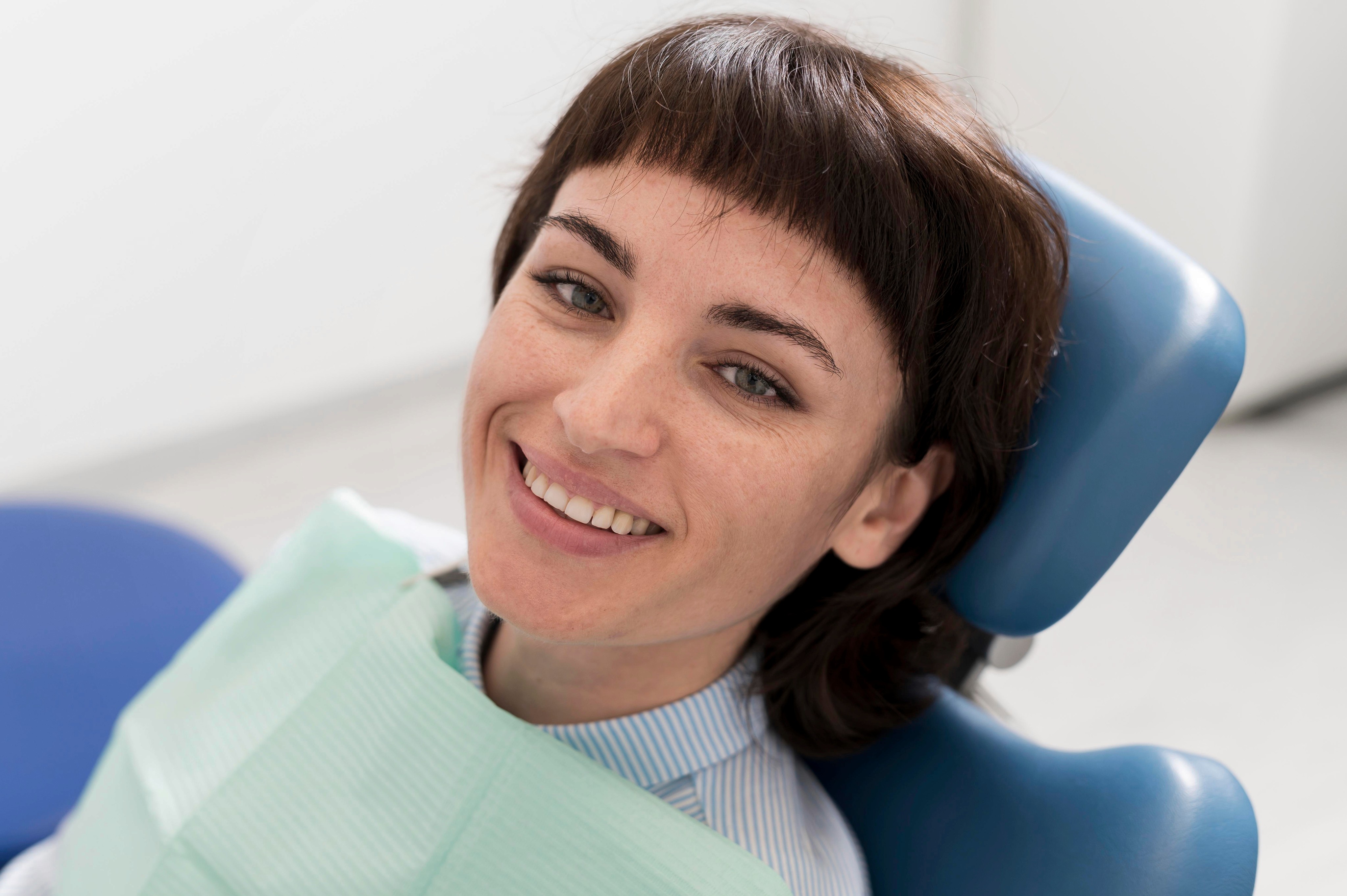 A female patient sitting in a dental chair, smiling and looking relaxed after a dental treatment.