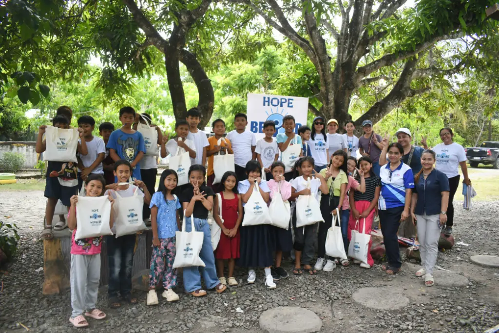 Students and volunteers holding Hope Beyond Measure bags under the trees