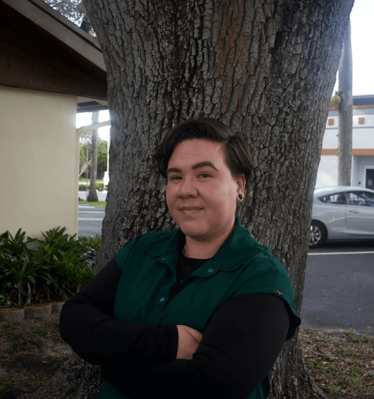karina with her arms crossed in front of a tree