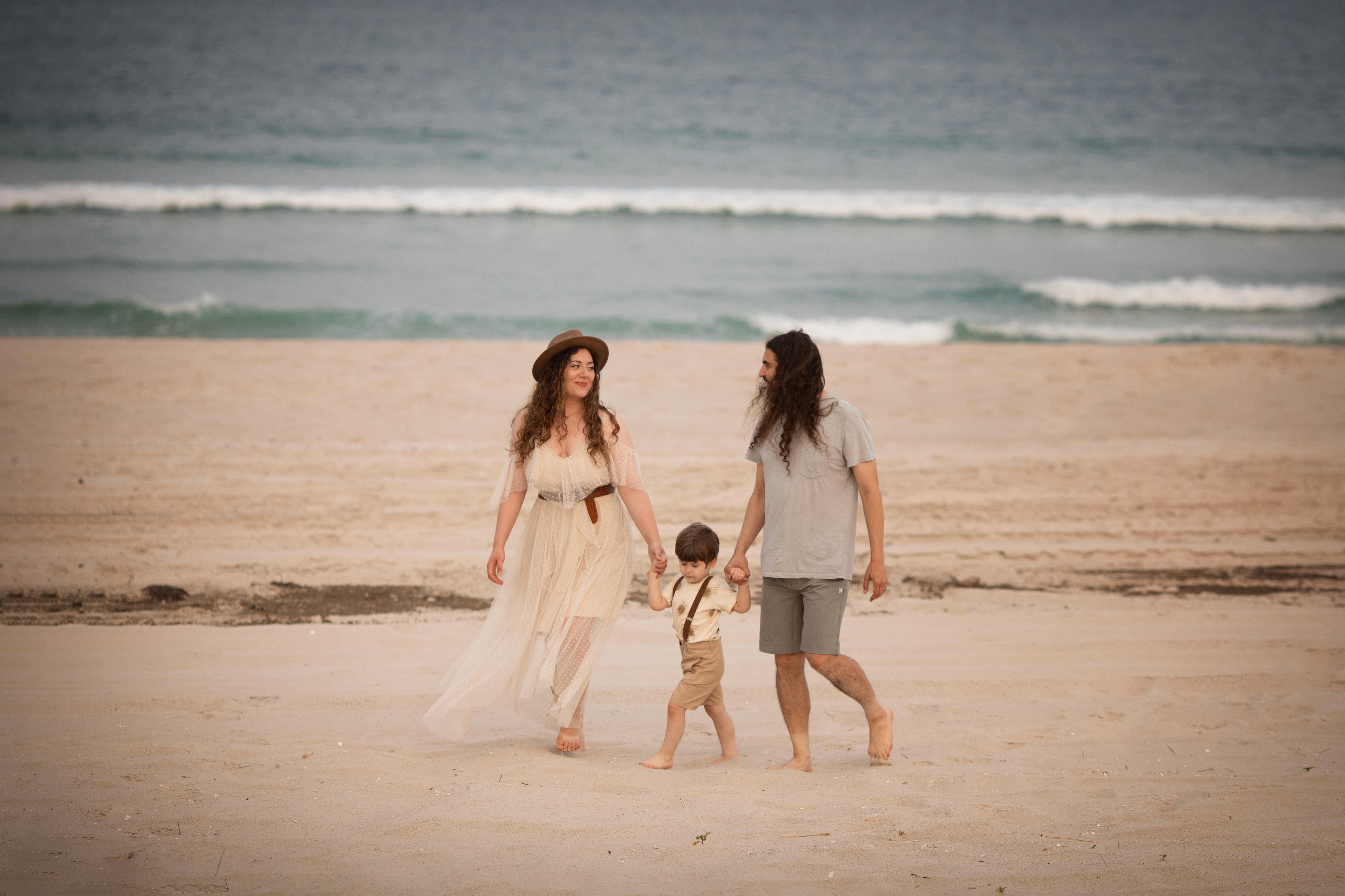 Family walking together under the coastal pier during a lifestyle photography session.