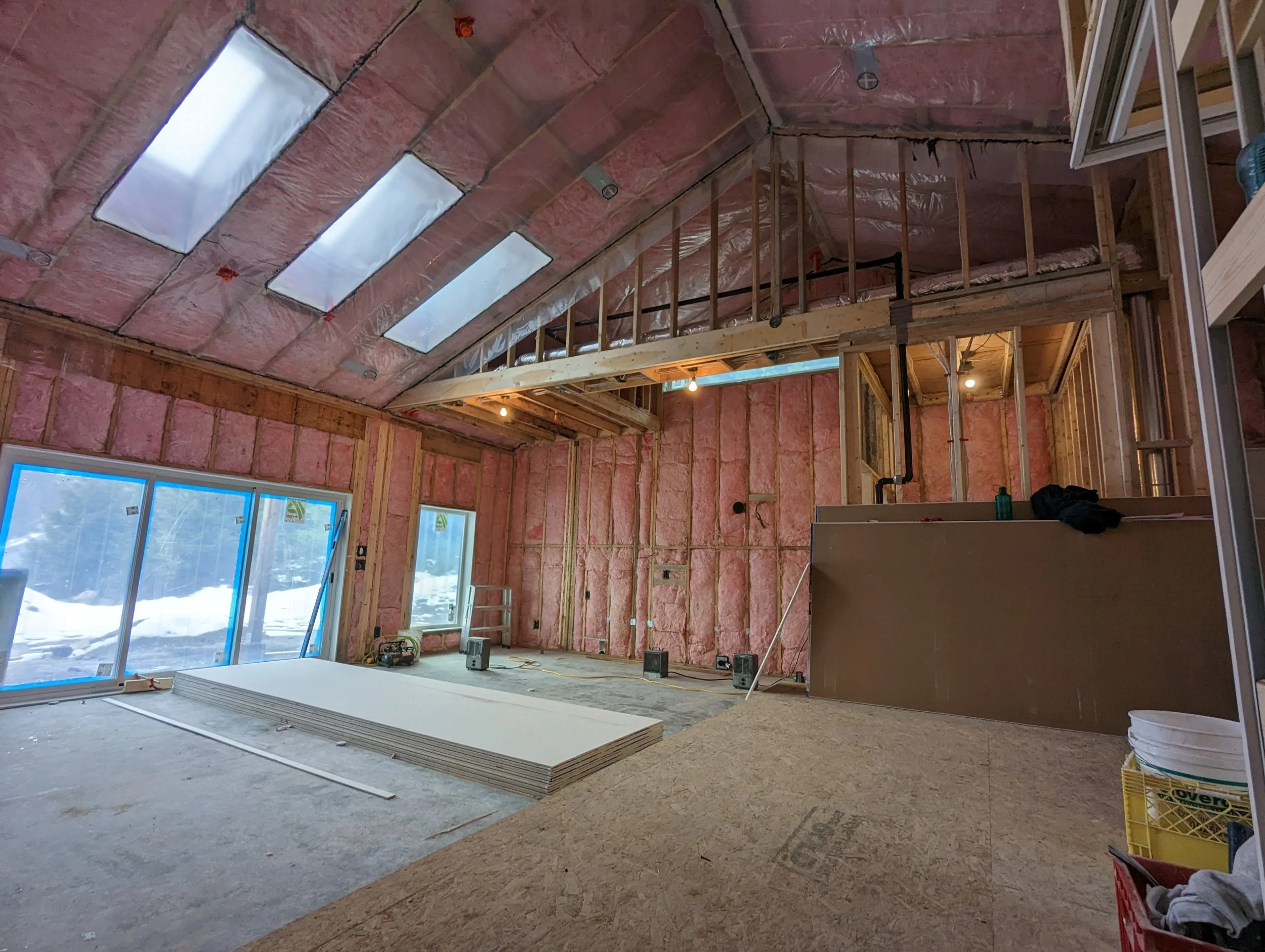 Modern two-story home with large glass windows, warmly lit interiors, and a balcony. Surrounded by trees and a manicured lawn at dusk. Cozy ambiance.