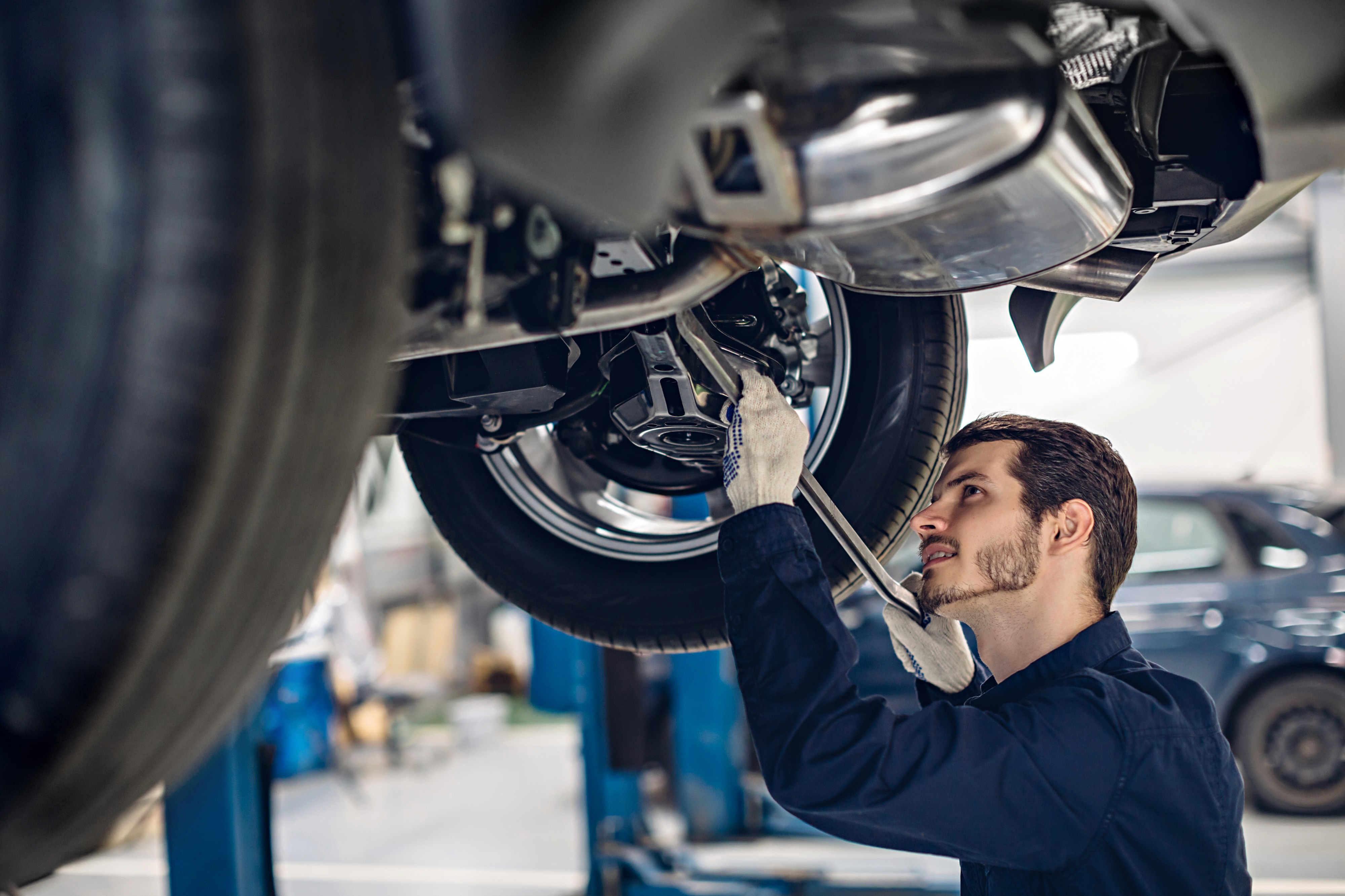 Professional technician performing vehicle undercarriage inspection