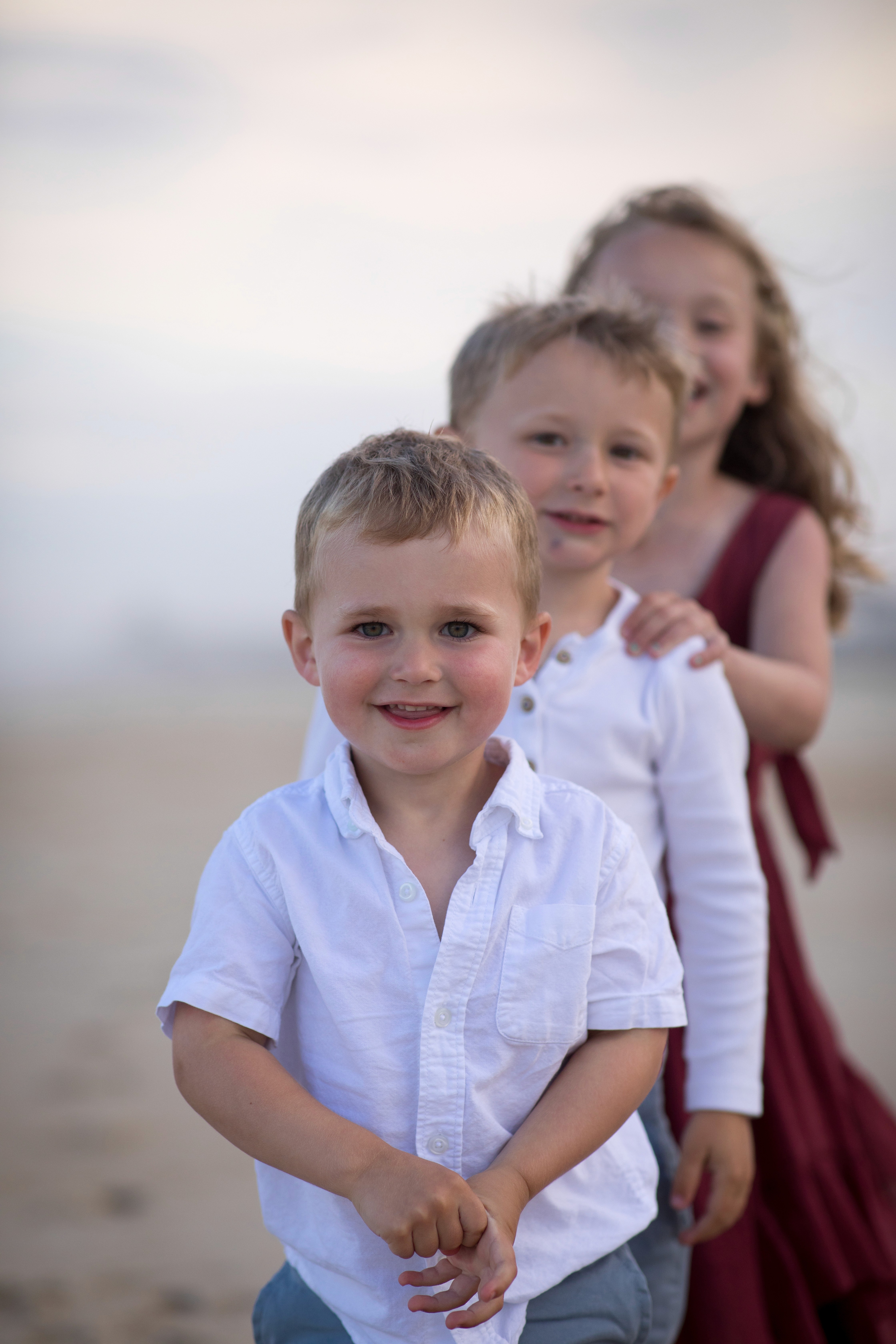 Family playing together during a beach session in San Diego at sunset.