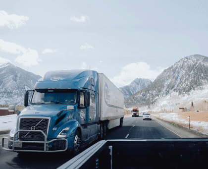 a blue semi truck driving down a mountain road
