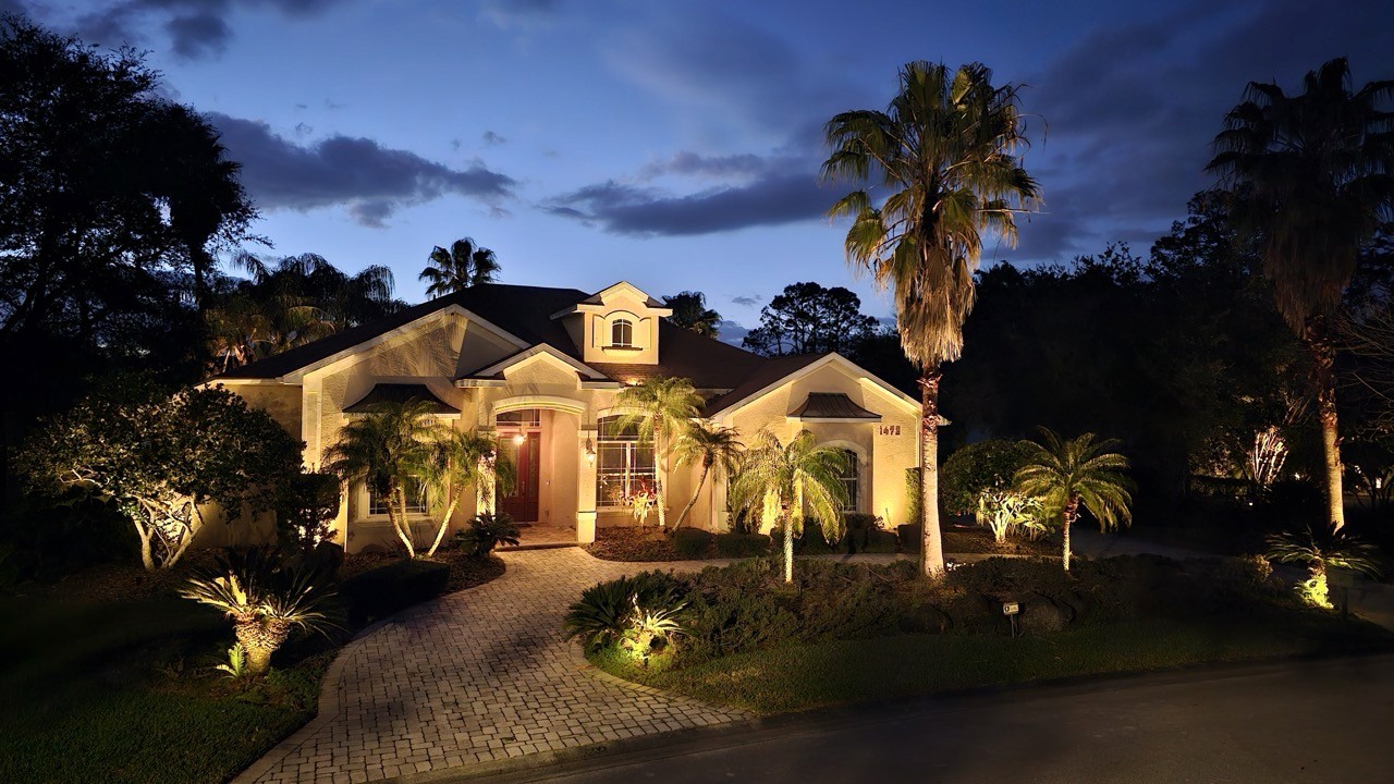Custom landscape lighting design highlighting driveway, entryway, and tropical landscaping