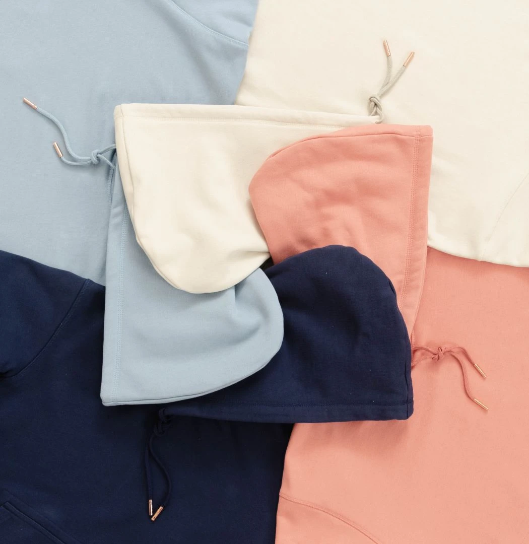 A smiling young man with crossed arms, wearing a plaid shirt and white t-shirt, poses against a dark background.