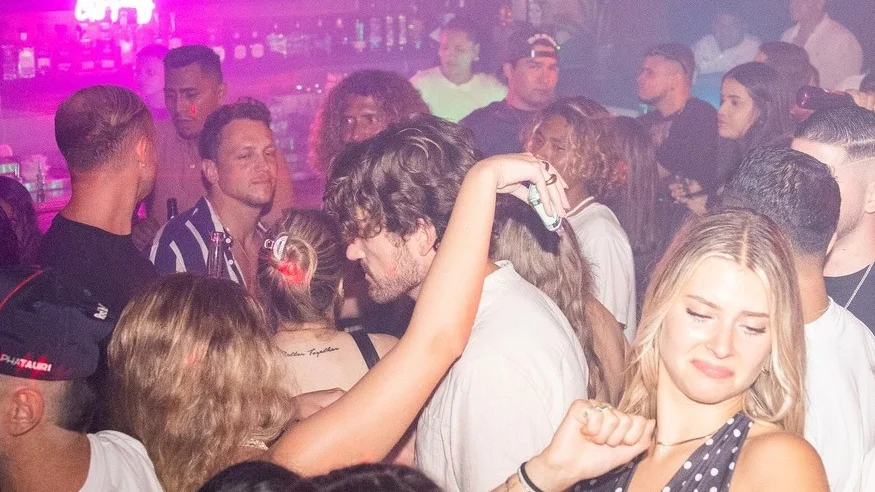 Crowd dancing in a bar under pink lights