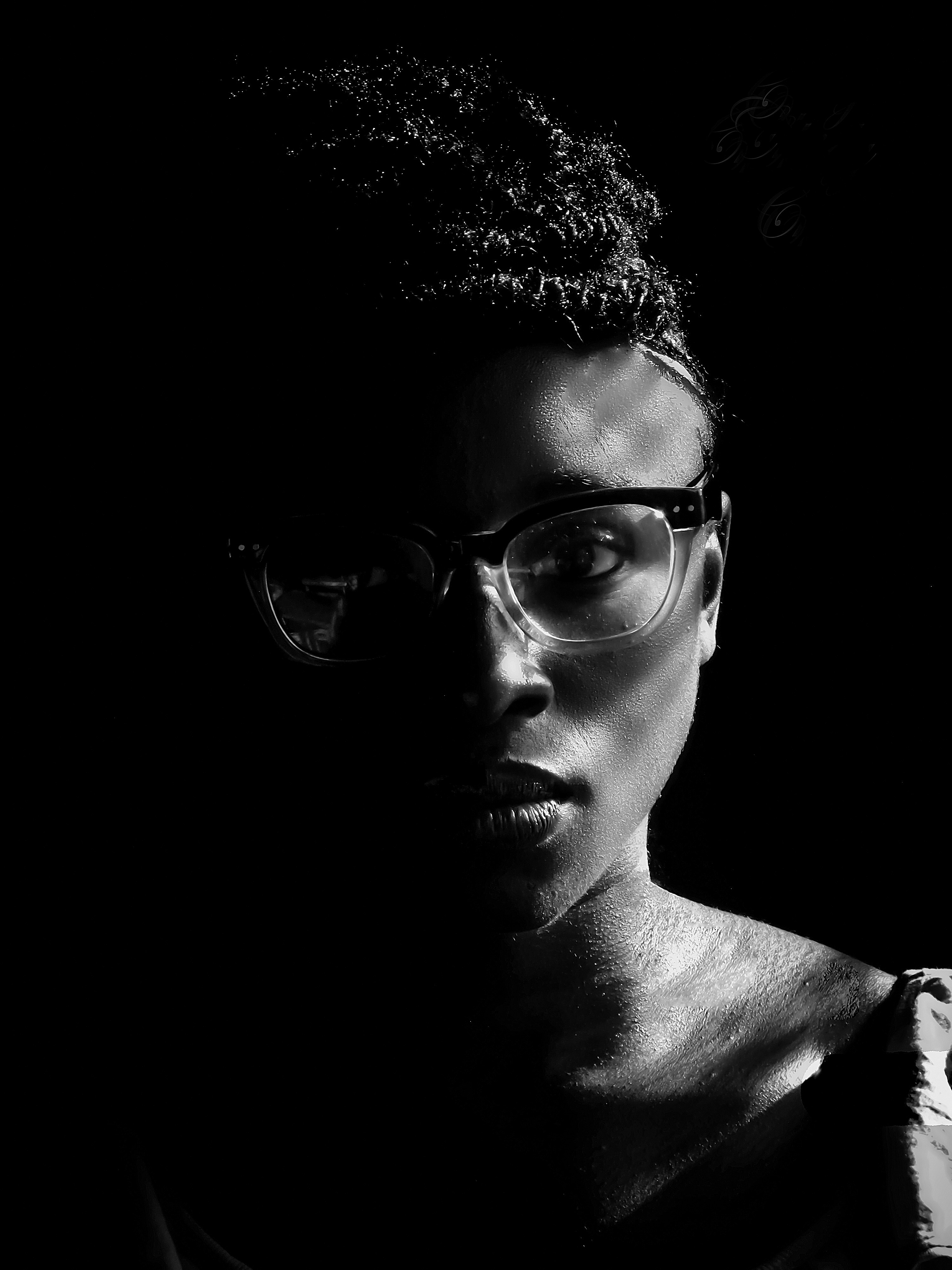A woman in glasses posed in dramatic lighting.