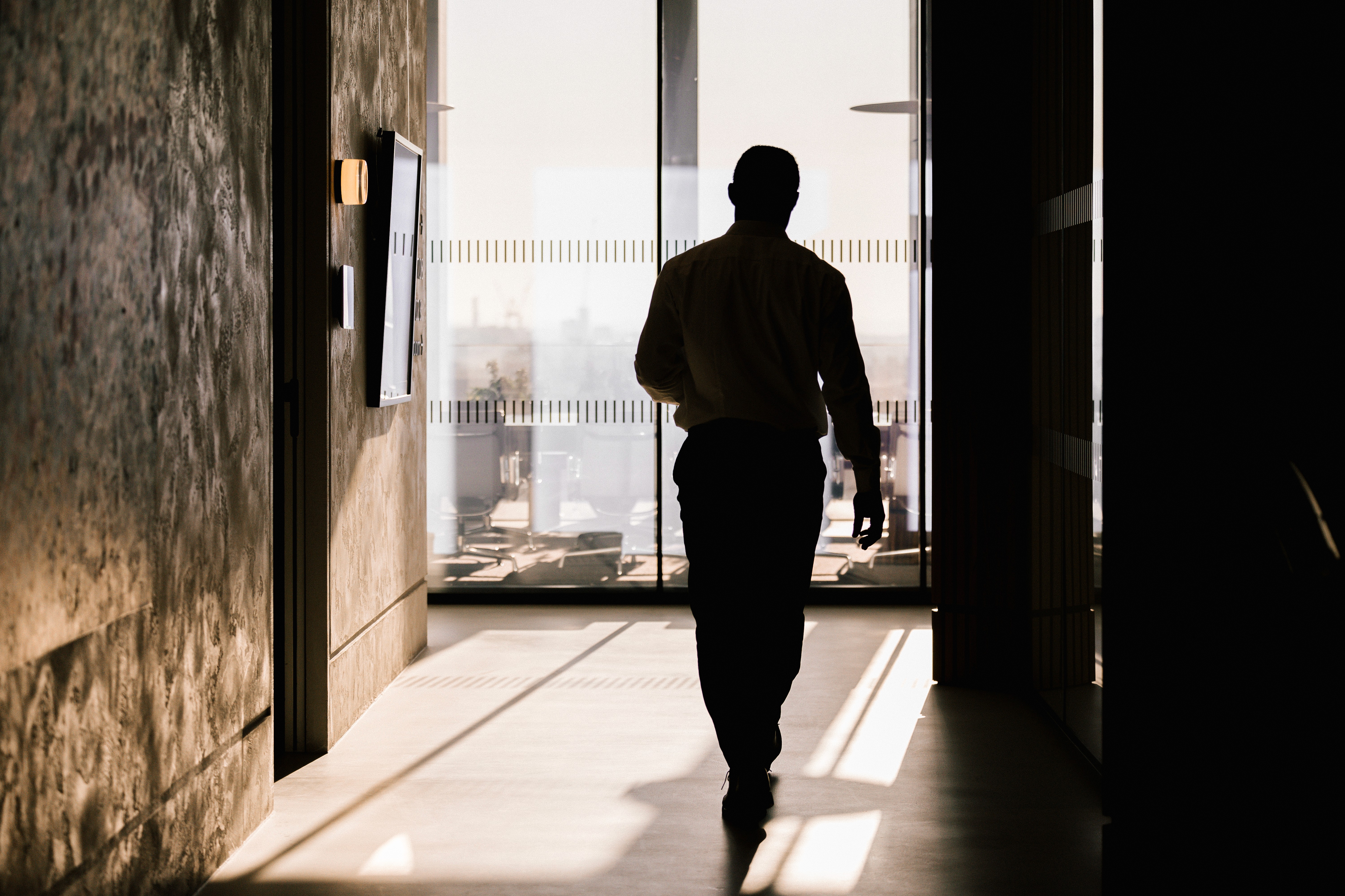 A suited legal professional walking through a modern office corridor, representing R & B Global Consultants' elite legal headhunting services