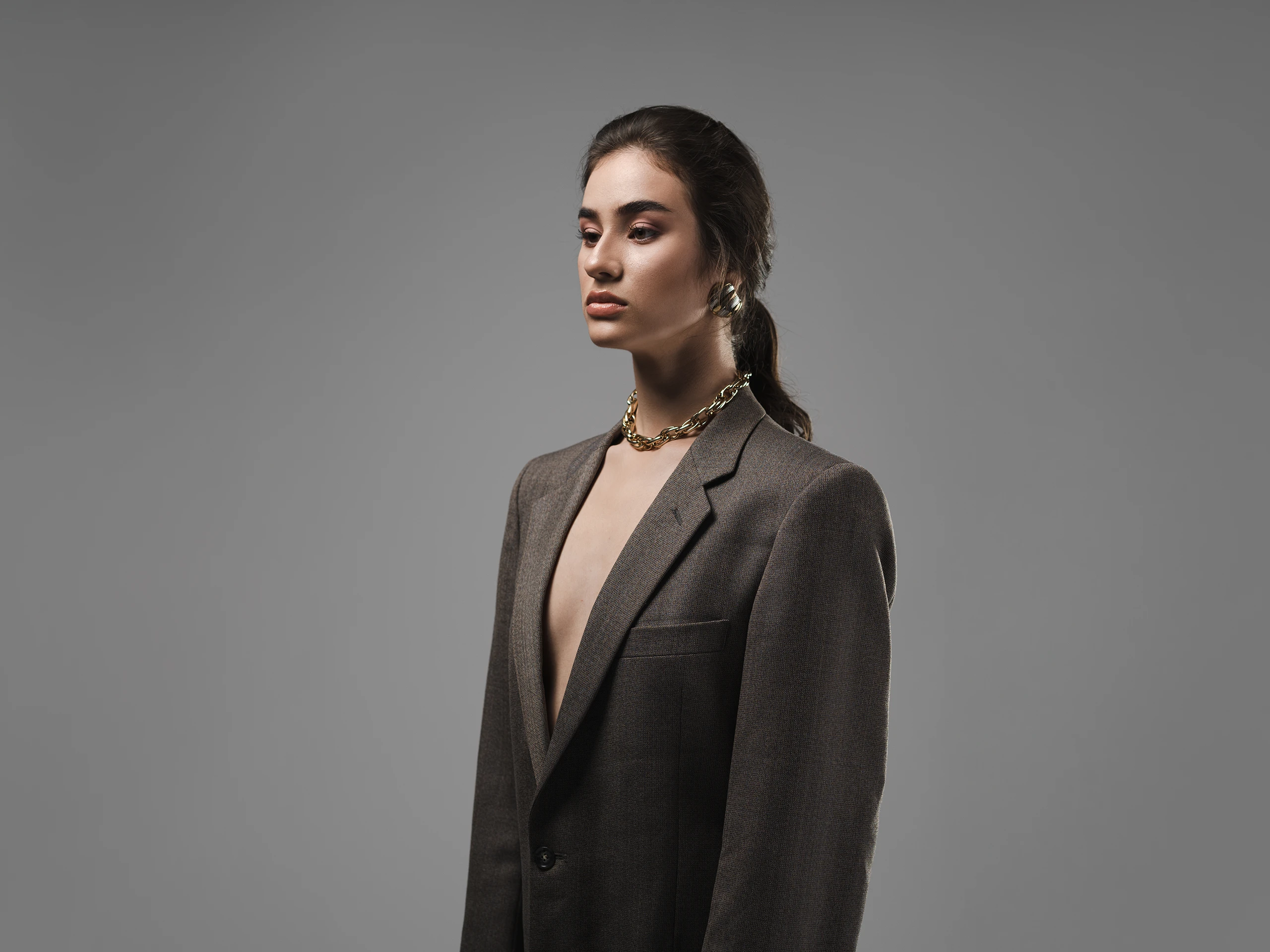 Editorial fashion portrait of a woman wearing an oversized blazer in a studio.