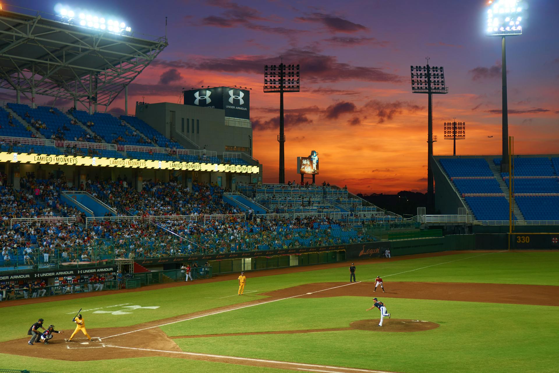 Baseball game in stadium at sunset, featuring players in action, spectators in stands, and illuminated stadium lights, highlighting the excitement of sporting events and luxury transportation services.