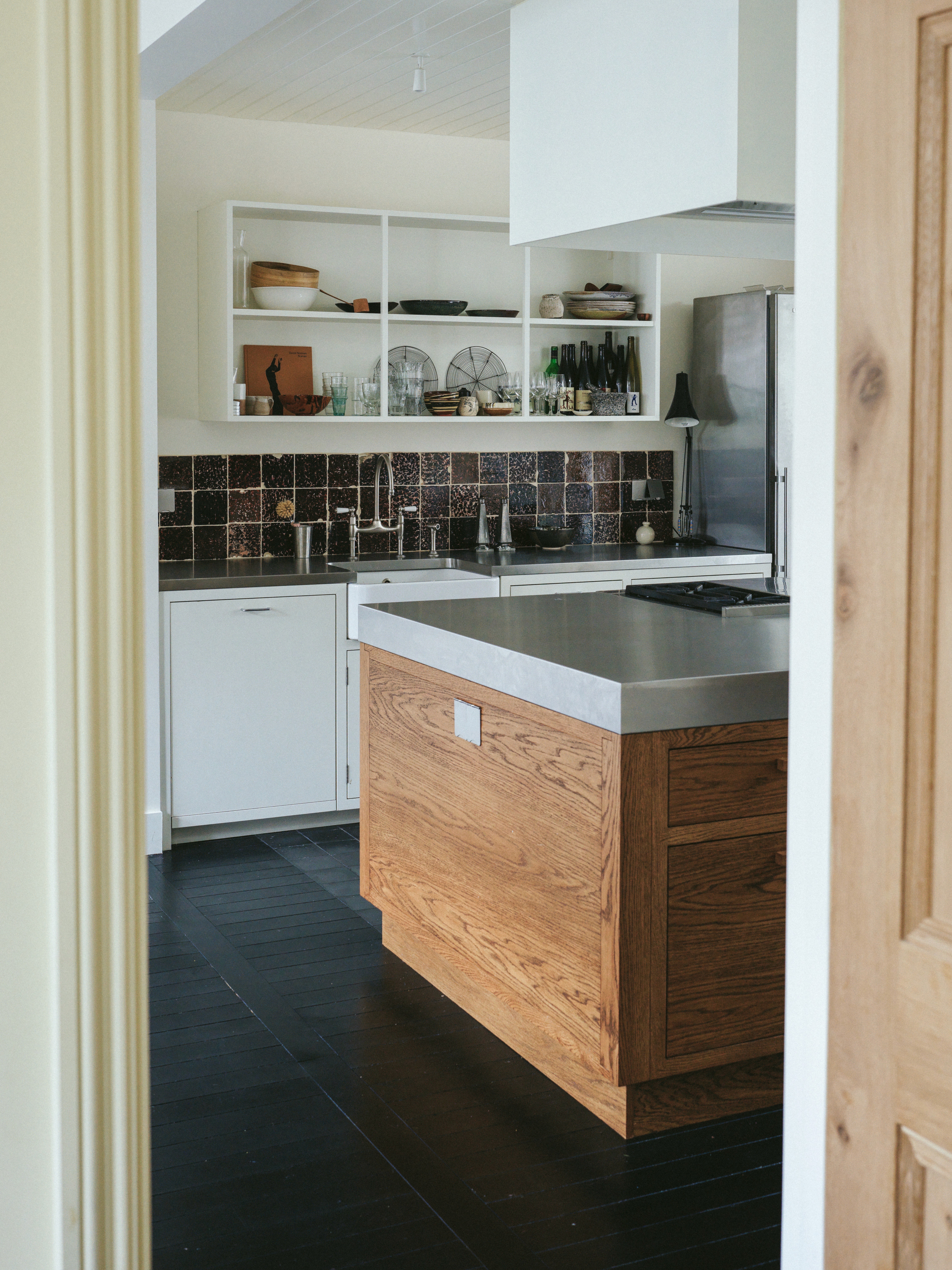 Framed kitchen view with oak island and polished black painted oak timber flooring